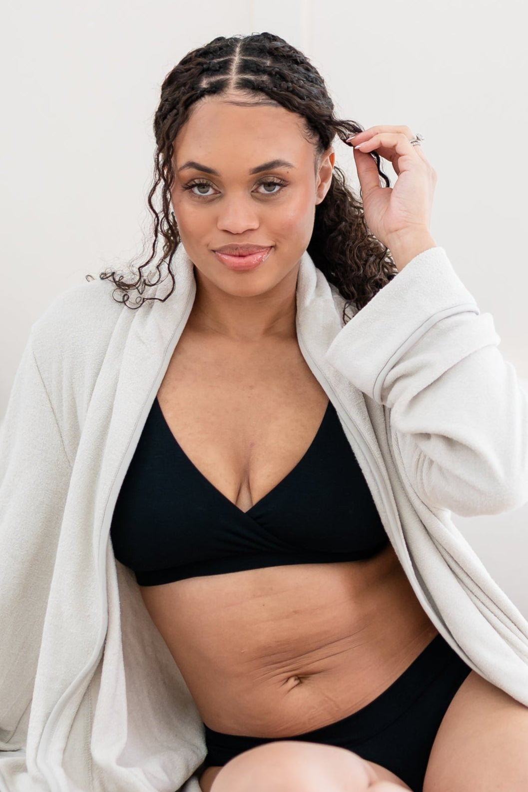 Woman in silky soft black bralette and underwear with a cream robe 