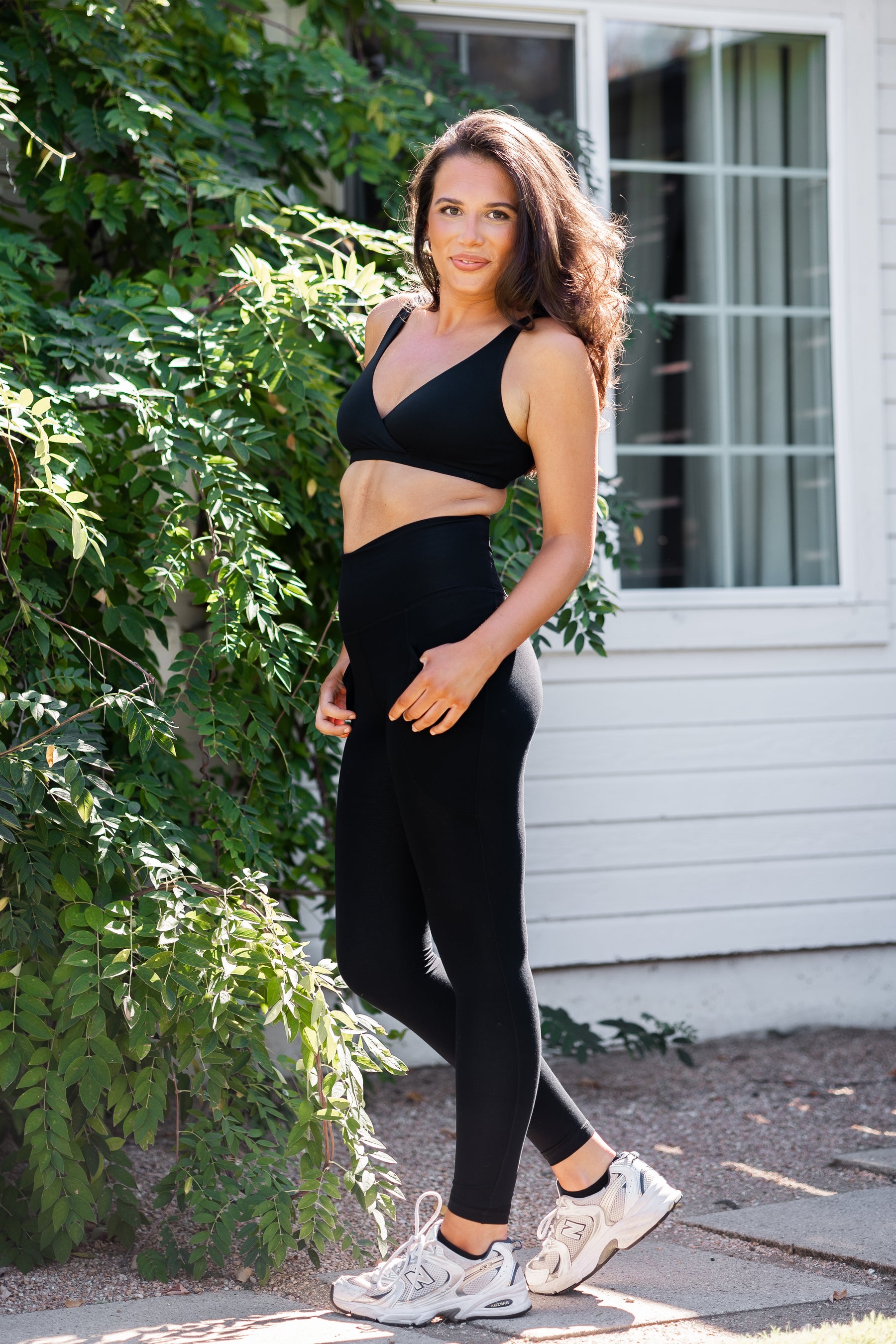 Female model posing wearing the Bamboo Flex Women’s Leggings in Midnight and matching cross front bralette