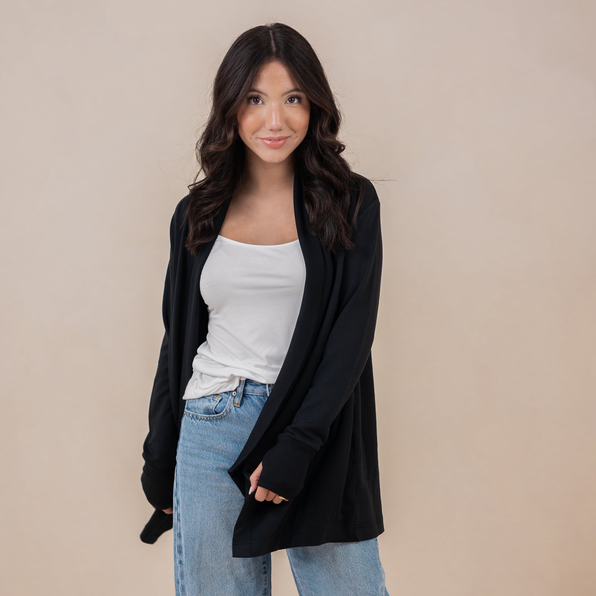 Female model standing wearing the Women's French Terry Wrap Top in Midnight paired with a white shirt and light wash jeans
