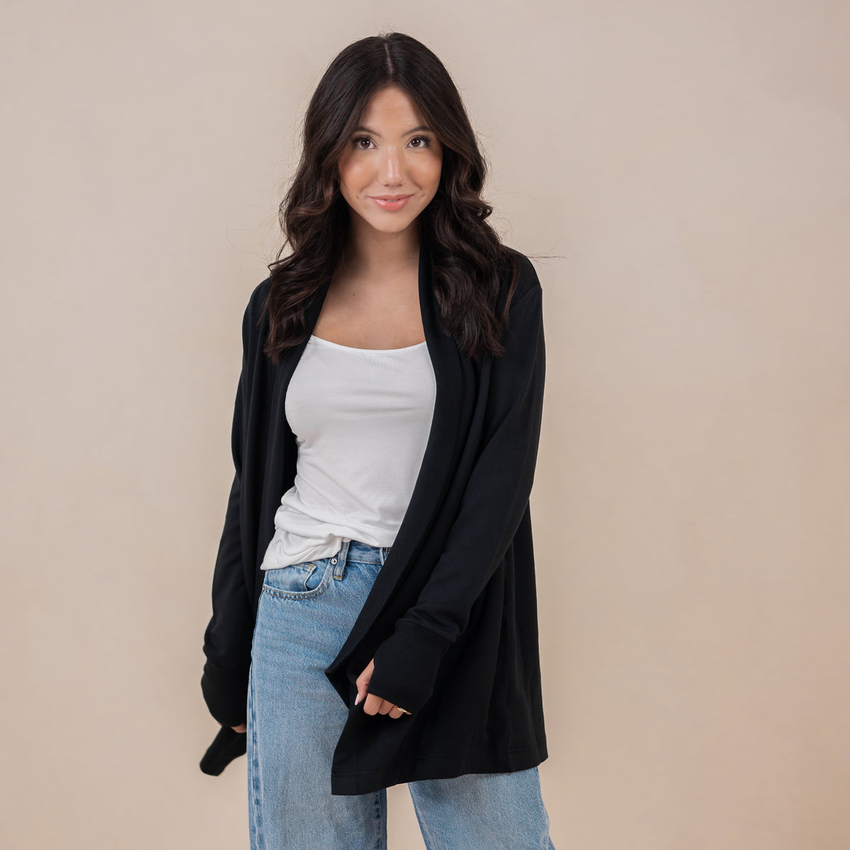 Female model standing wearing the Women's French Terry Wrap Top in Midnight paired with a white shirt and light wash jeans