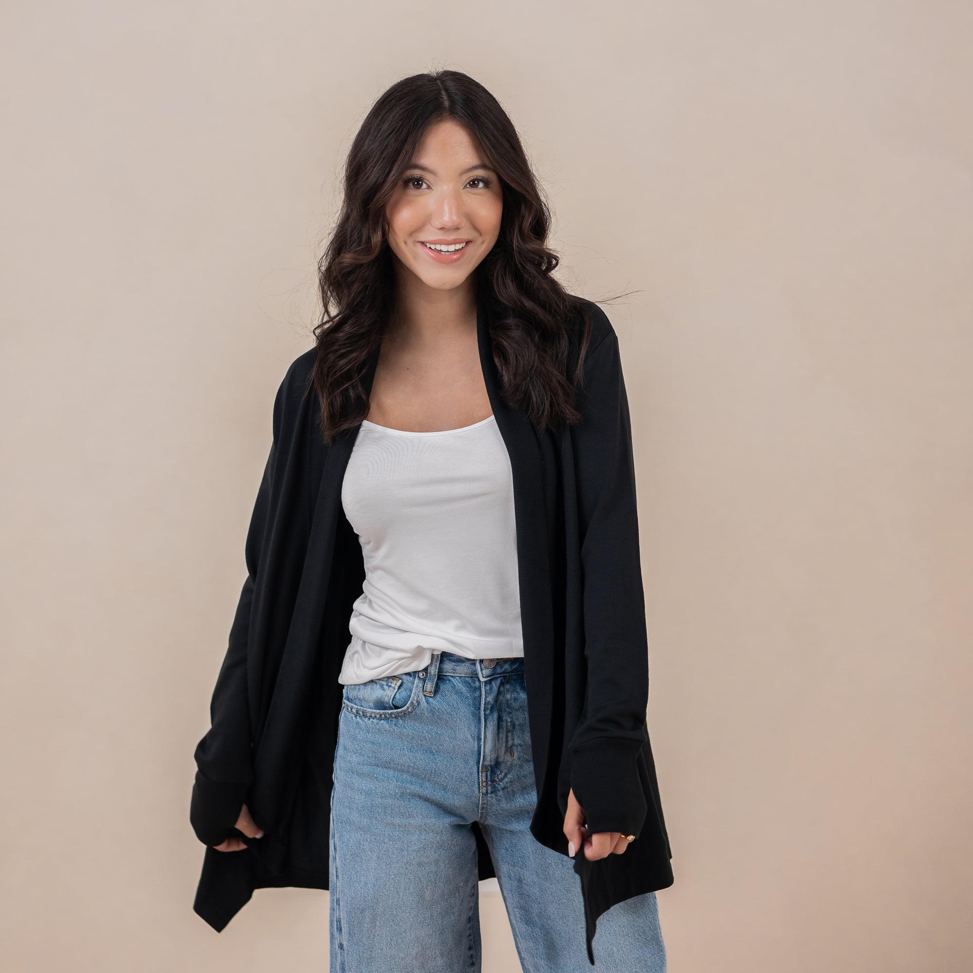 Smiling model wearing the Women's French Terry Wrap Top in Midnight paired with a white shirt and light wash jeans