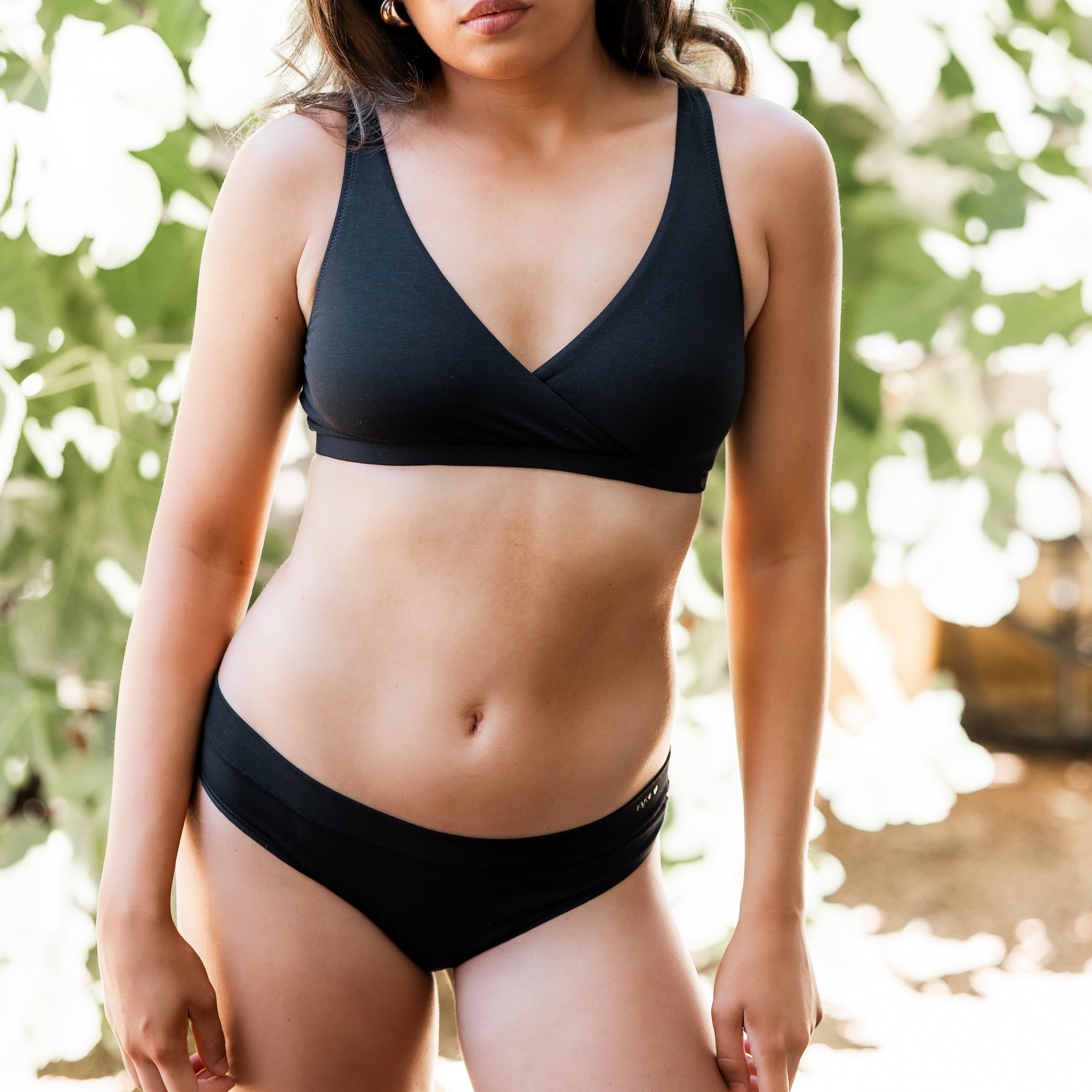 Woman wearing a black underwear set with a blurred natural background