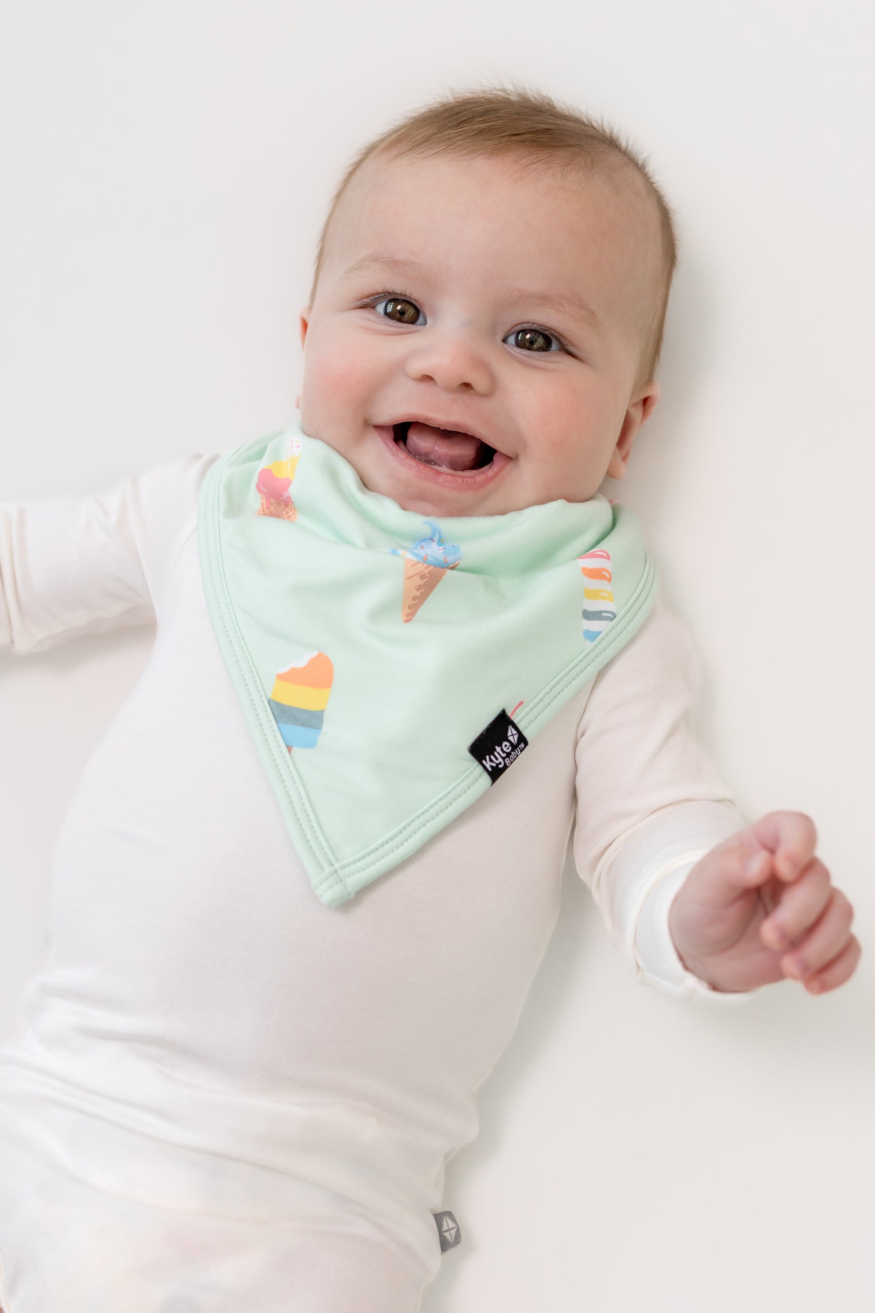 Baby smiling in Mint Ice cream print Bib over a white bodysuit on a white background