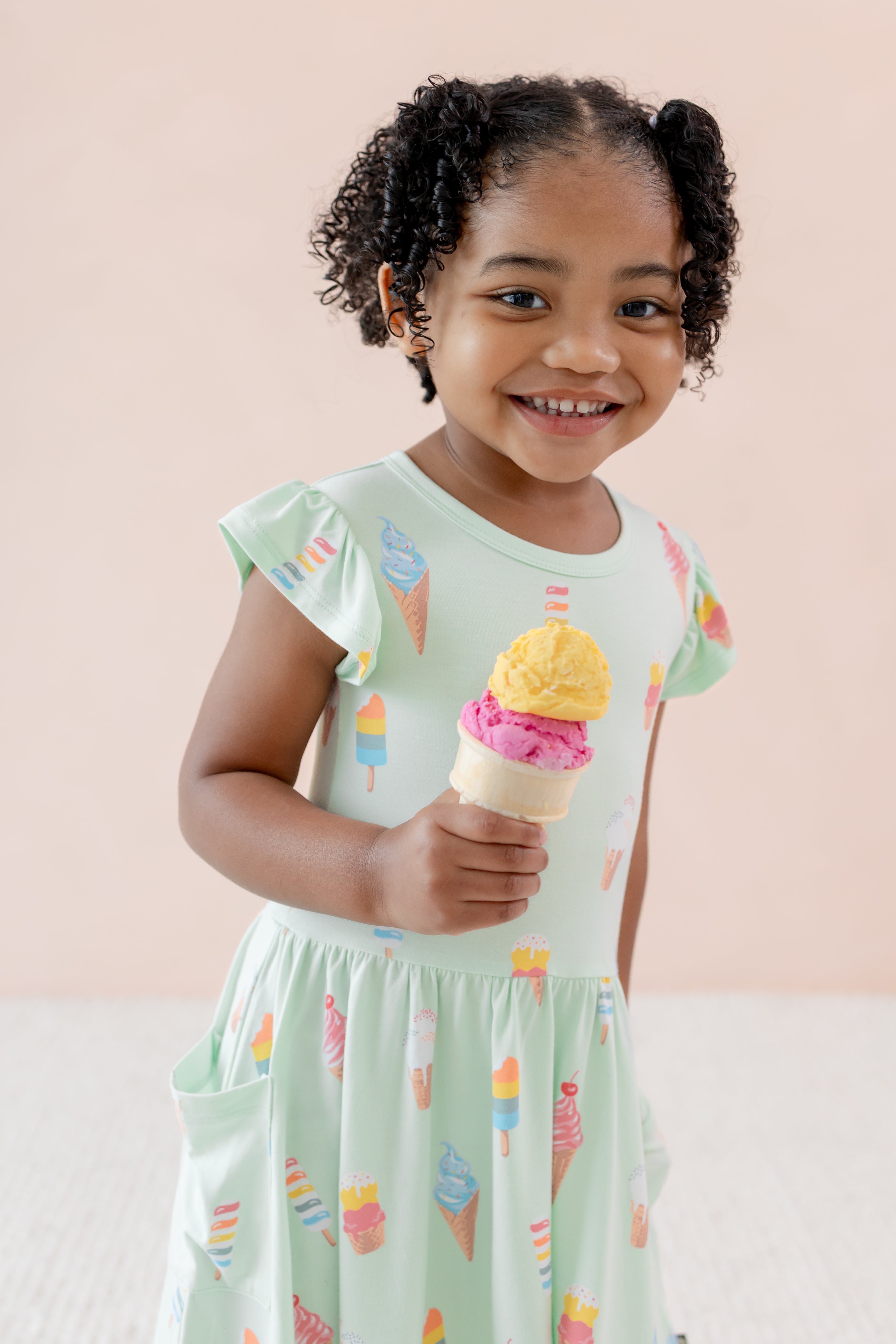 Child smiling holding an ice cream wearing Mint Ice Cream print Pocket Dress on a beige background
