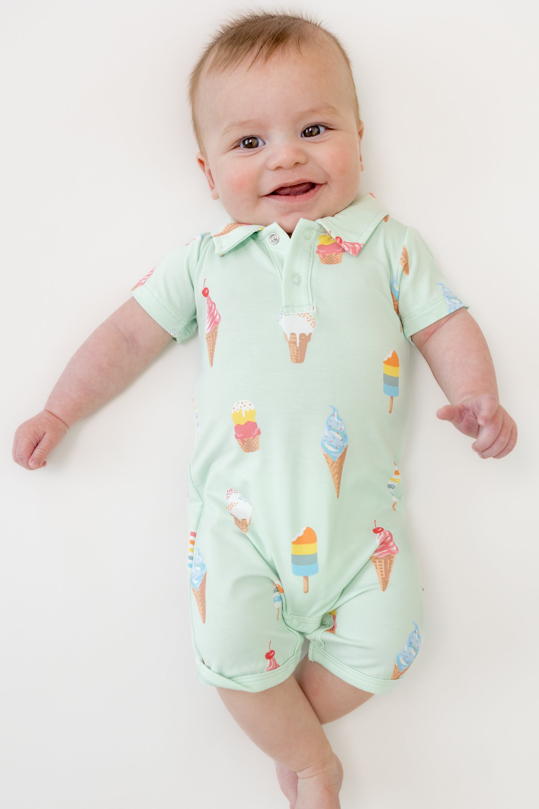 Baby smiling in Mint Ice Cream Polo Shortall on a beige background