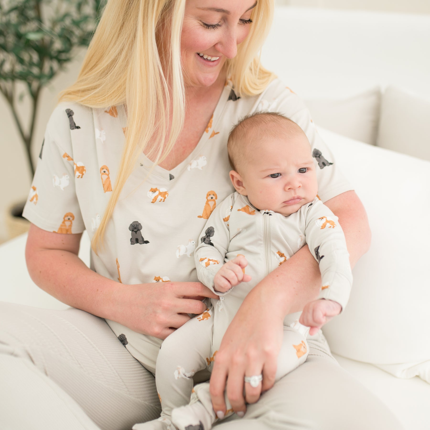 Close up of mother wearing the Women’s Relaxed Fit V-Neck in Fluffy Dog holding her infant wearing a matching zippered footie