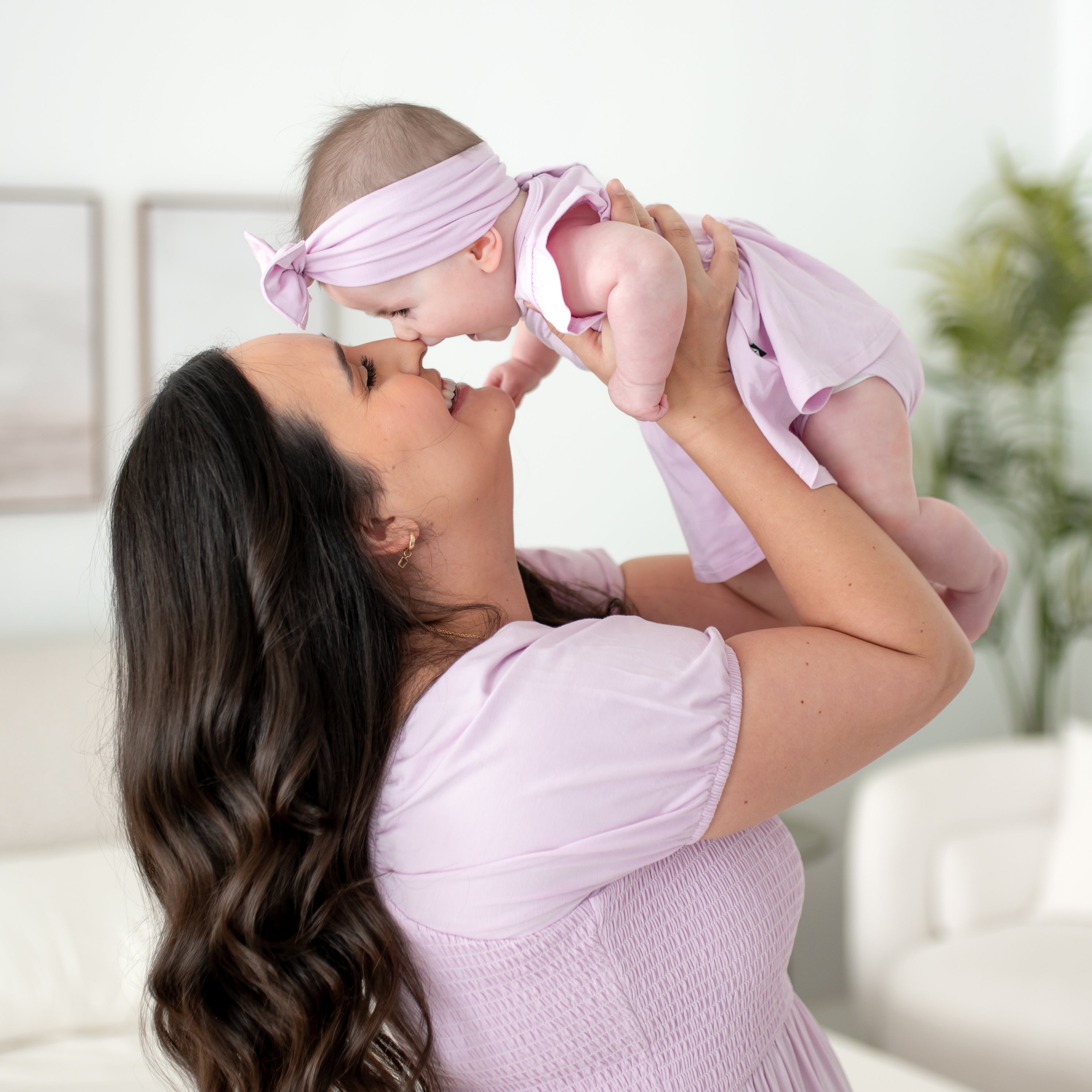 Woman holding a baby in a purple outfit with a blurred background