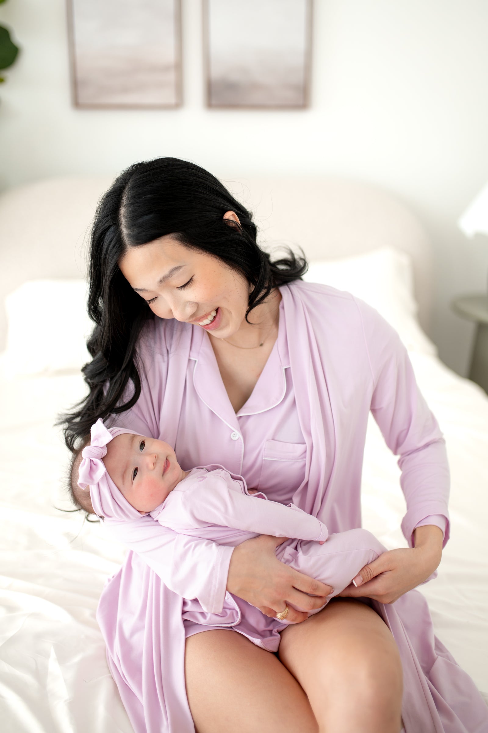 Woman wearing a light purple PJ set and robe holding baby in matching outfit