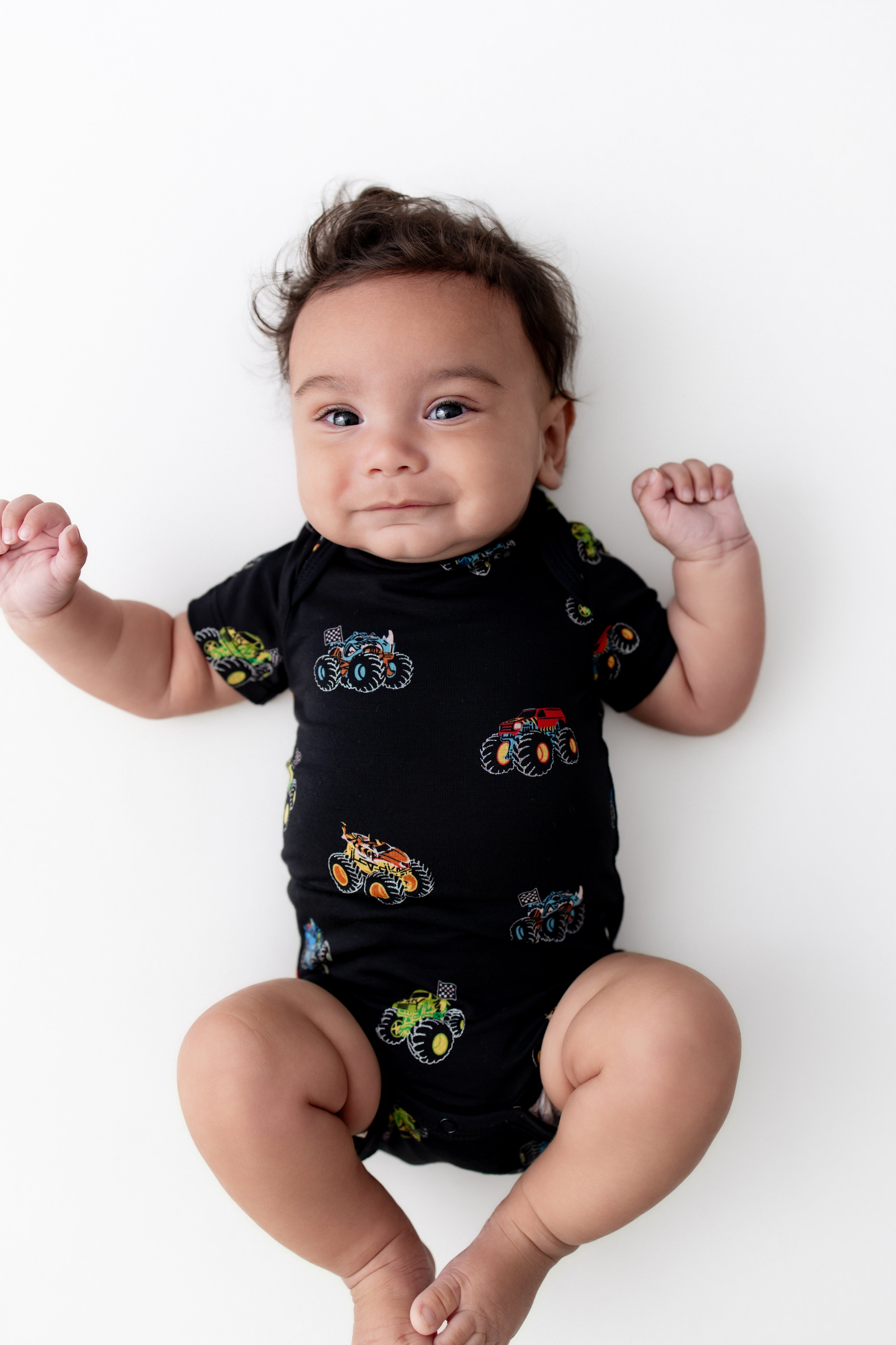 Baby in Black Bodysuit in Monster Truck print on white background