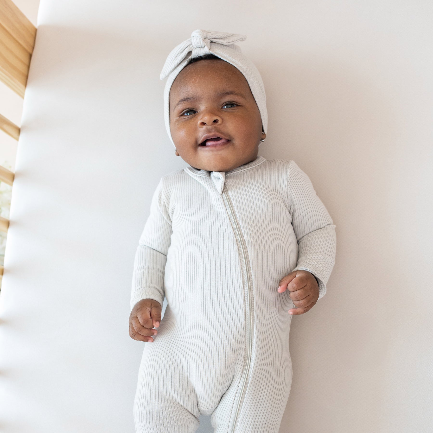 Baby wearing Kyte Baby bamboo Ribbed Zippered Footie in Oat