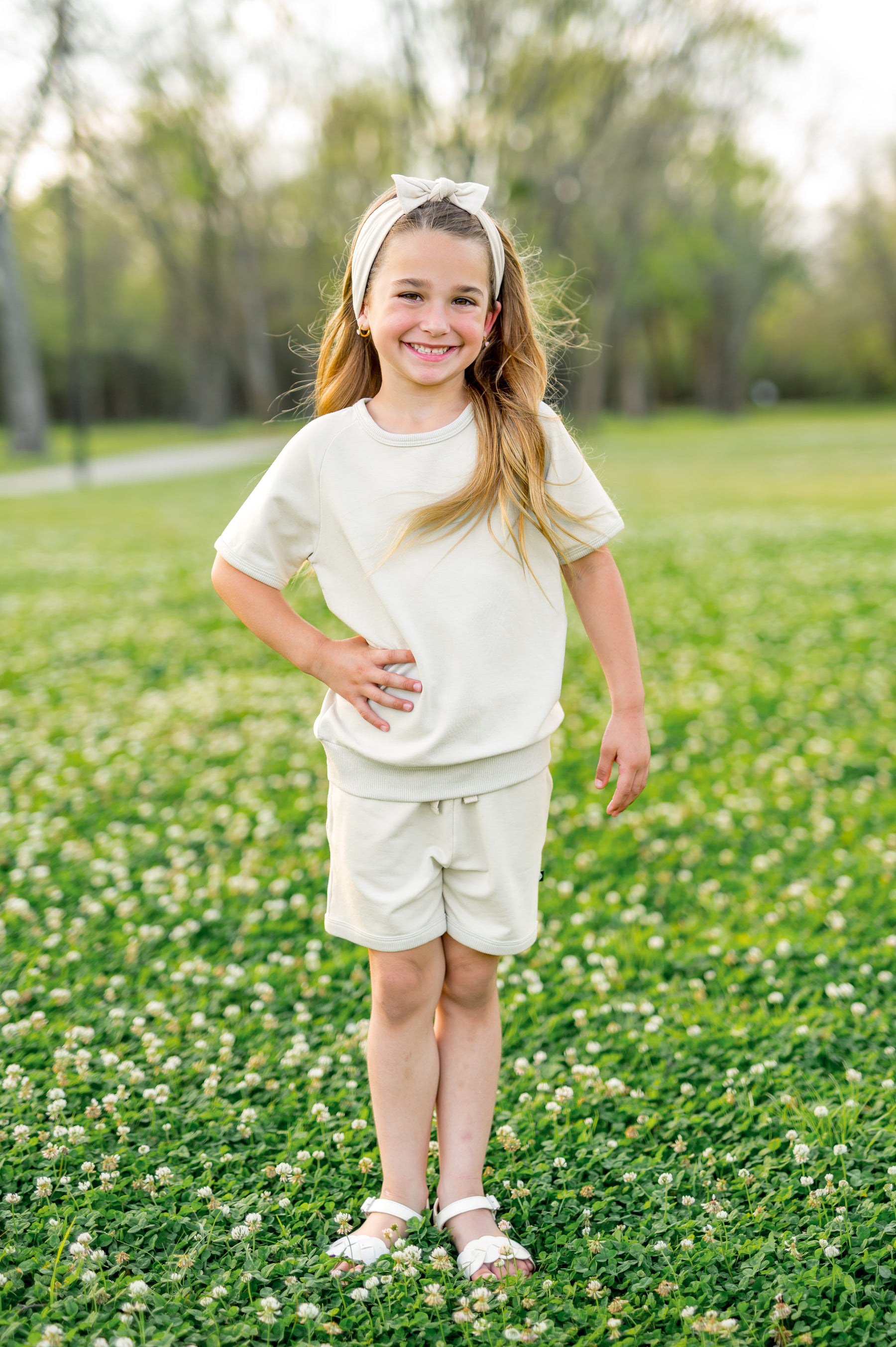 Young girl standing in a field with her hand on her hip wearing the Short Sleeve Jogger Set in Oat