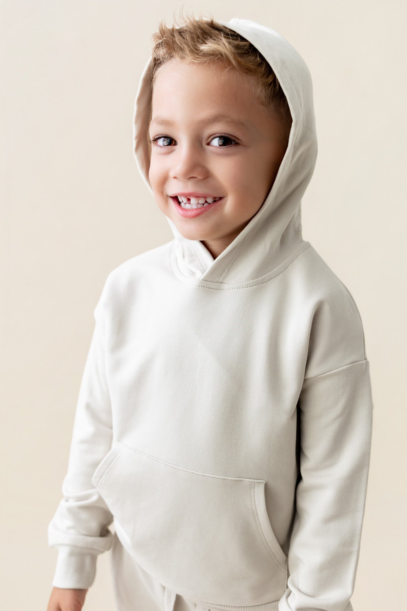 Boy wearing Hoodie in Oat color on a beige background