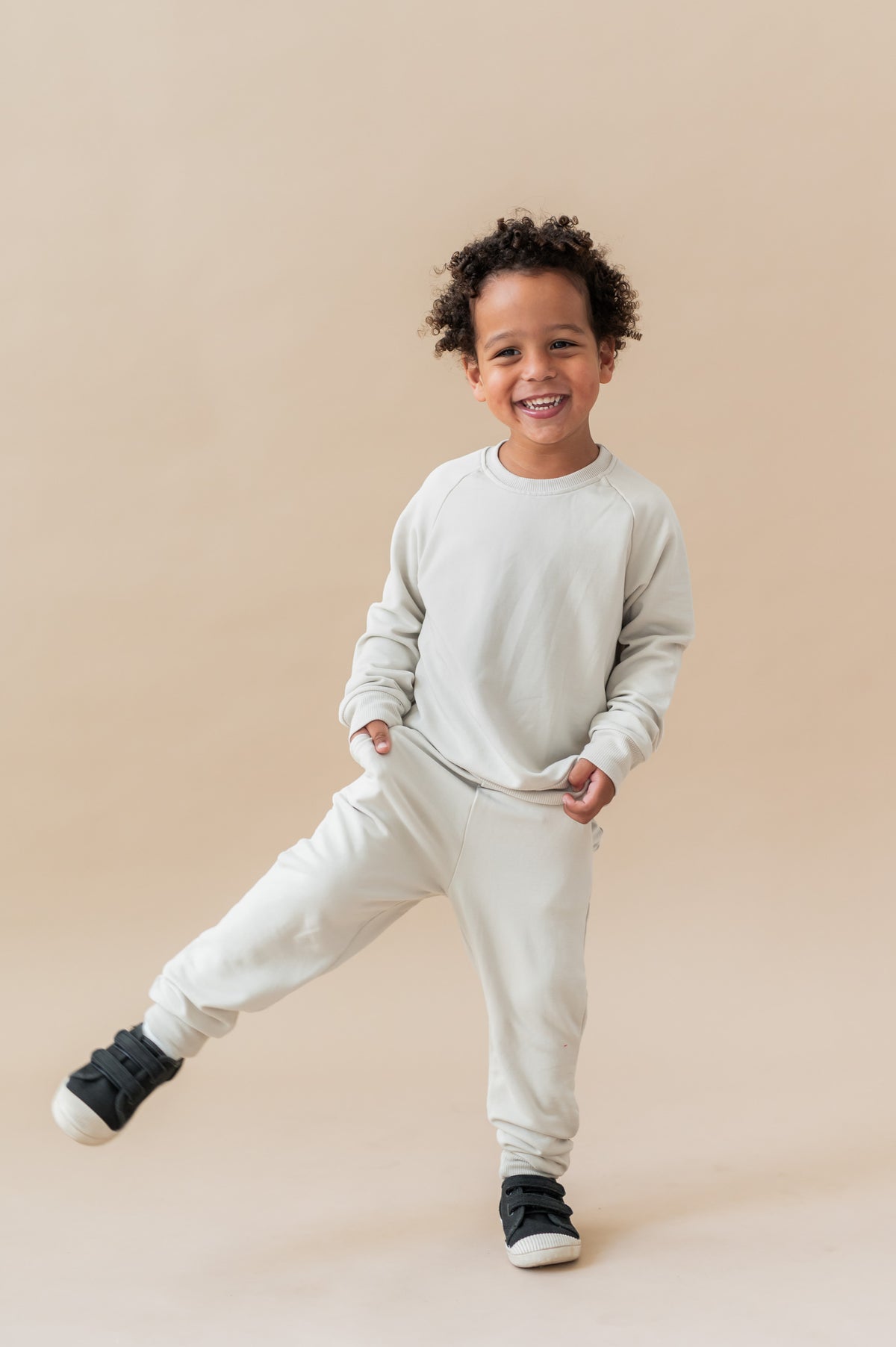 Boy posing in Long Sleeve Jogger Set in Oat color on a beige background