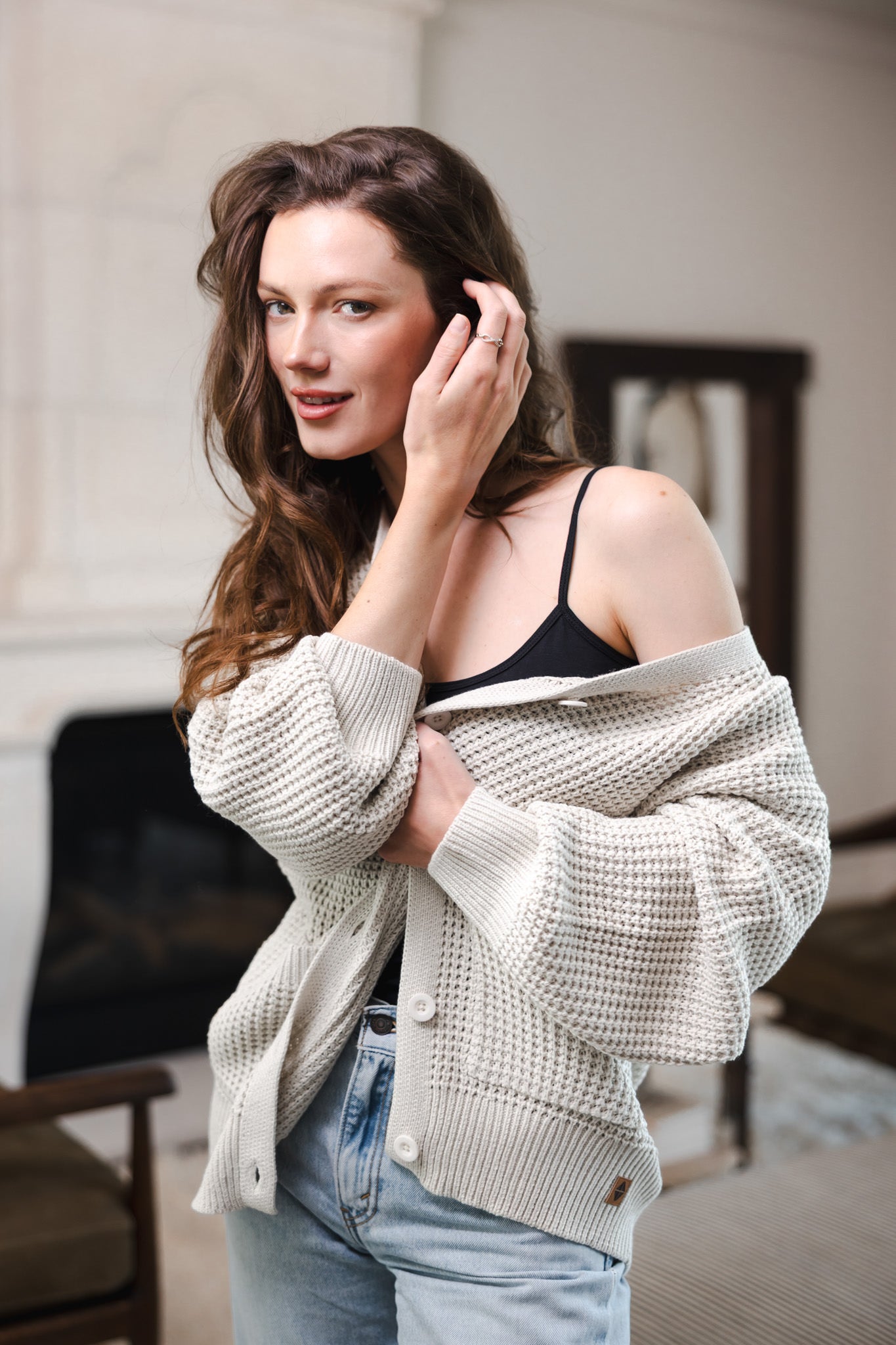 Modal posing in Chunky Knit Women's Waffle Cardigan in Oat over black camisole and a blue jeans
