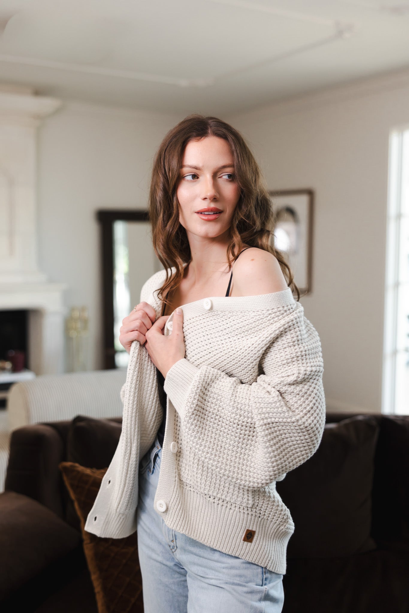 Modal wearing Chunky Knit Women's Waffle Cardigan in Oat over a blue jeans standing in a living room