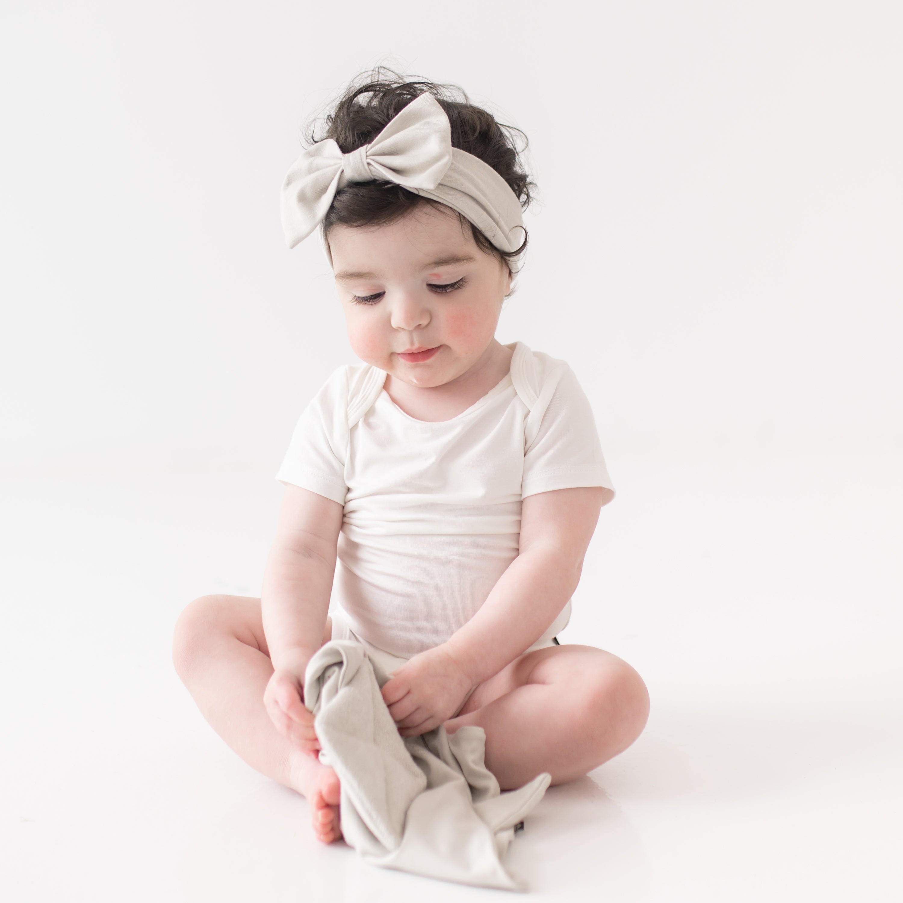 Baby wearing Bow Headband in Oat while holding Kite Lovey