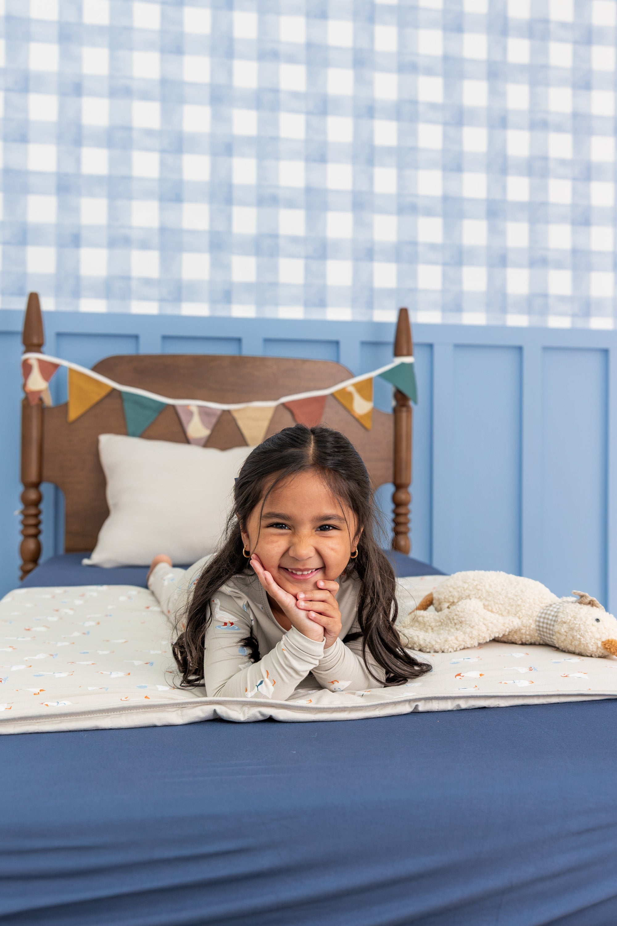 Girl wearing Long Sleeve Pajamas in Oat Silly Goose print lying on belly on a bed