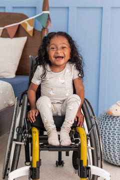 Toddler wearing Short Sleeve with Pants Pajamas in Oat Silly Goose print sitting on a wheel chair