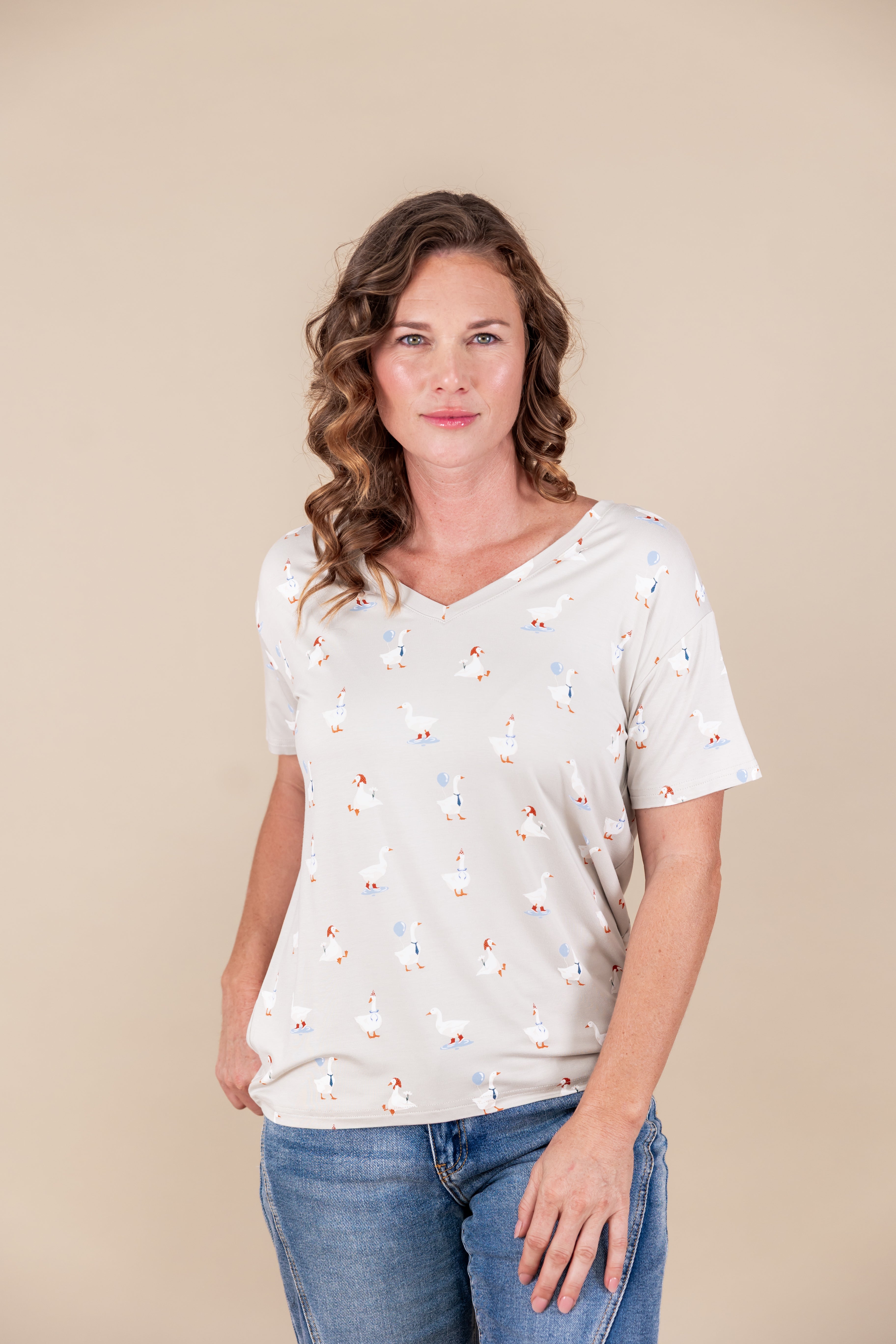 Modal wearing Women's Oversized V-Neck in Oat Silly Goose print over blue jeans on a beige background