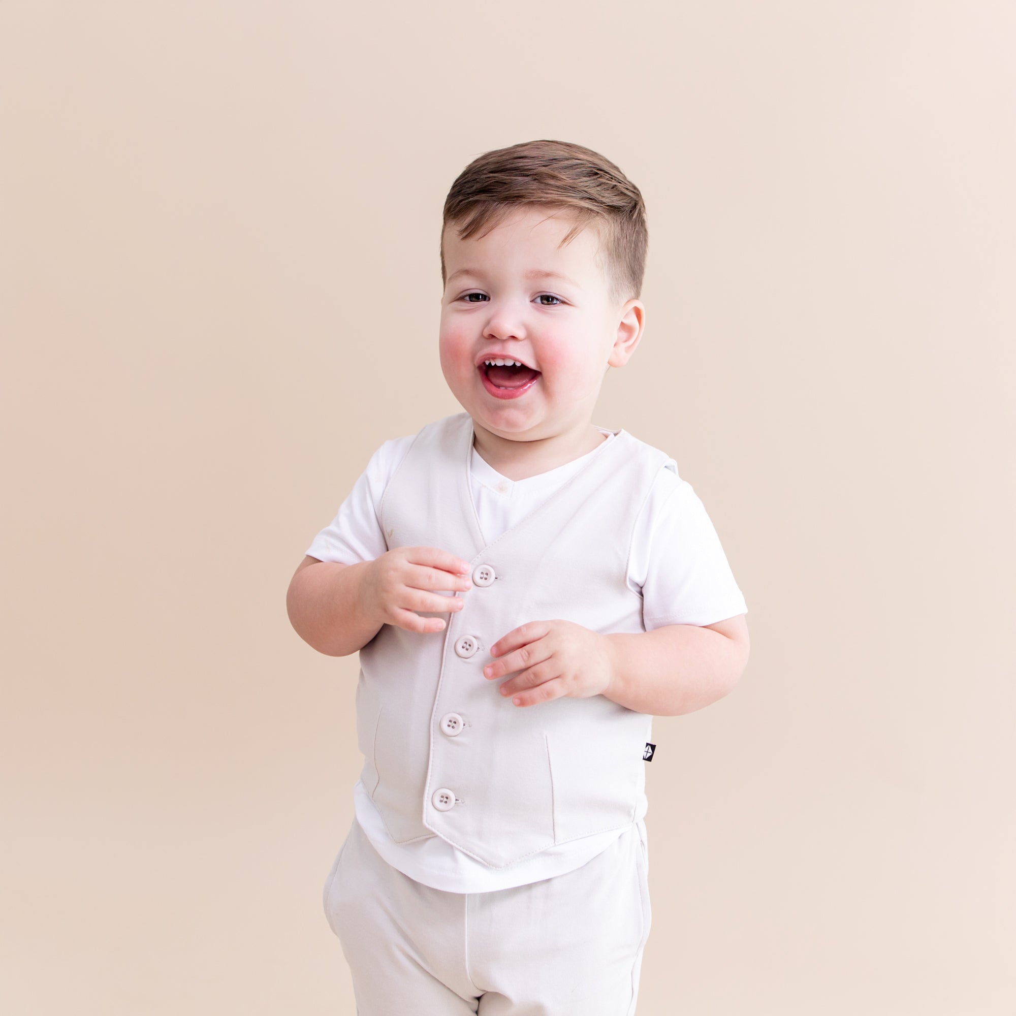 Young toddler wearing the Tuxedo Vest in Oat overtop a white v-neck shirt