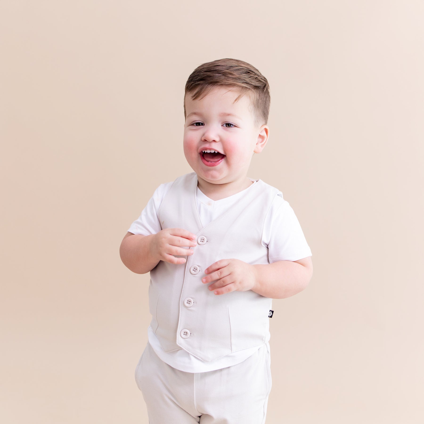 Young toddler wearing the Tuxedo Vest in Oat overtop a white v-neck shirt