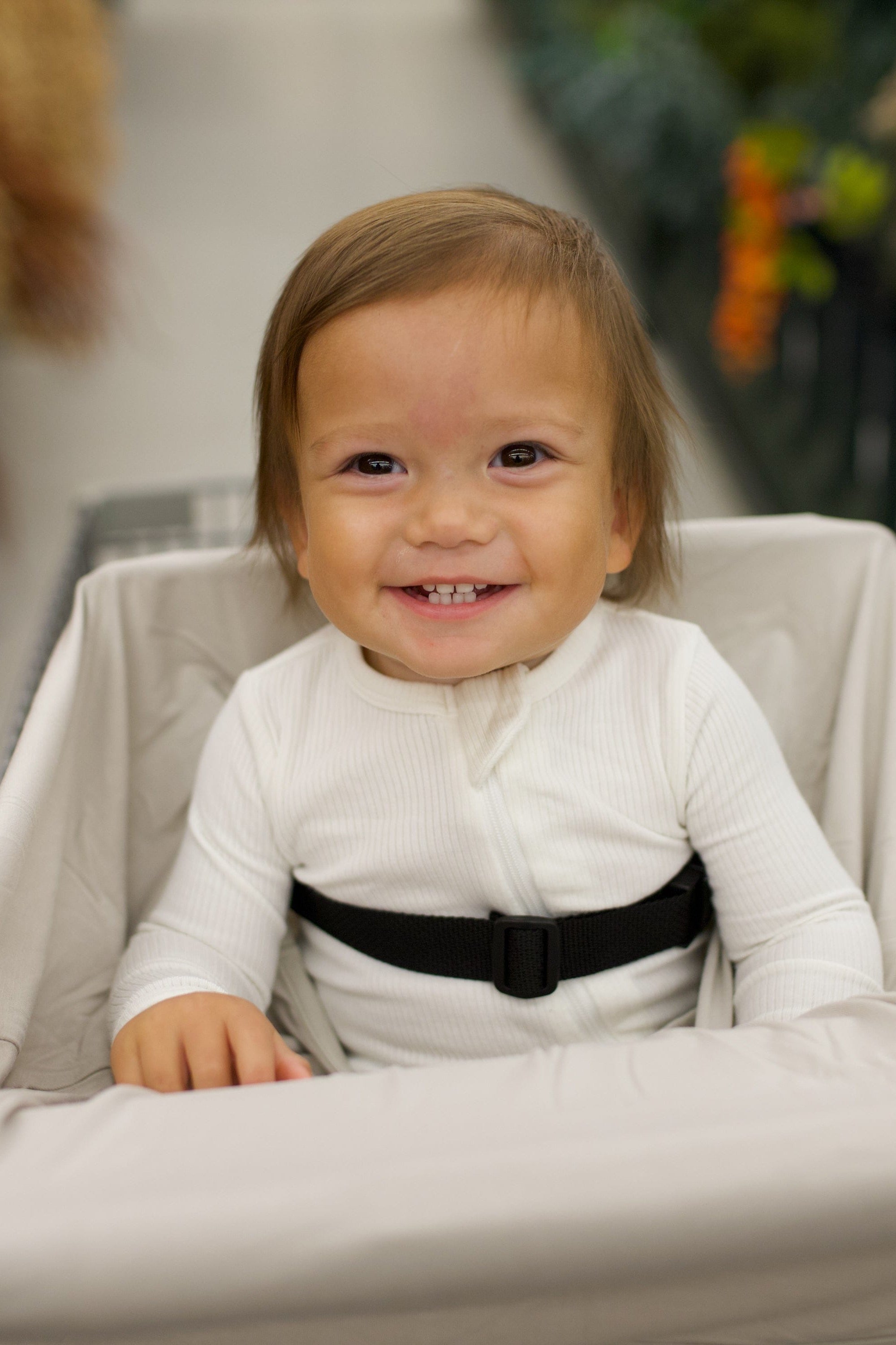 Child in a shopping cart with a cover on the cart with a blurred floral background