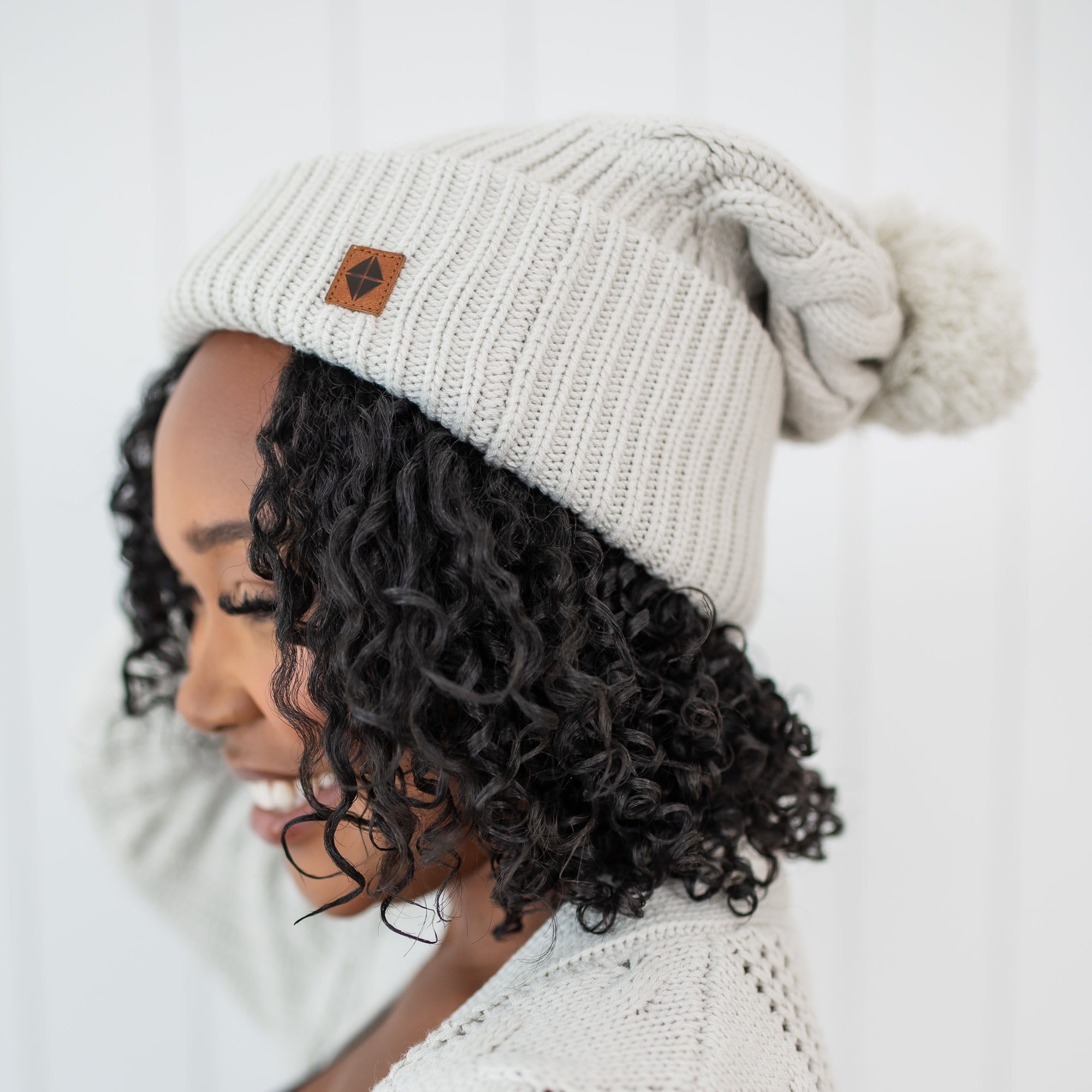 Close up on the Cable Knit Adult Pom Beanie in Oat shown on a female model