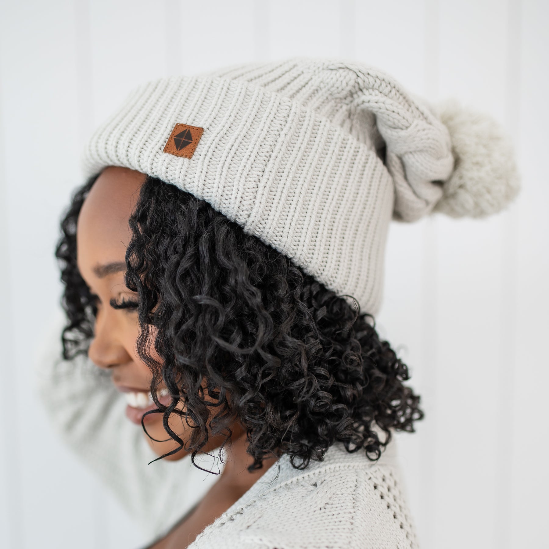 Close up on the Cable Knit Adult Pom Beanie in Oat shown on a female model