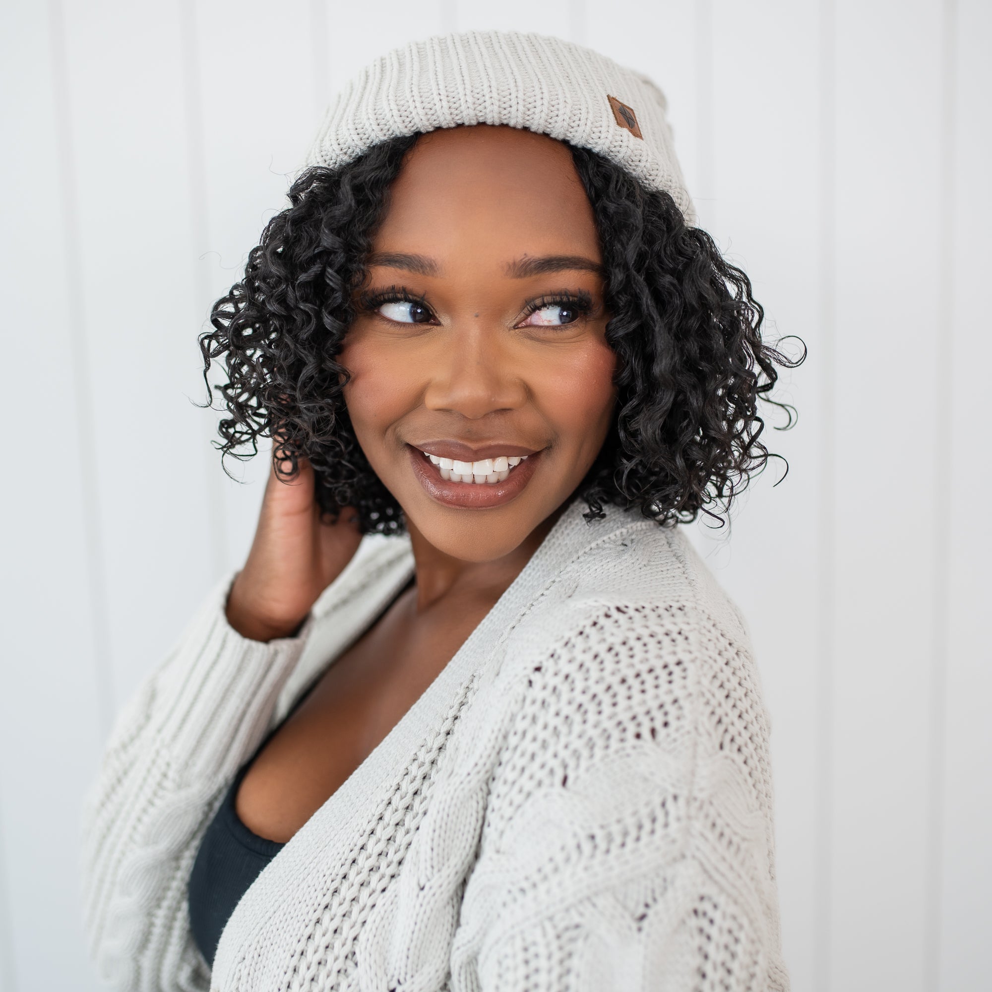 Smiling female model wearing the Cable Knit Adult Pom Beanie in Oat
