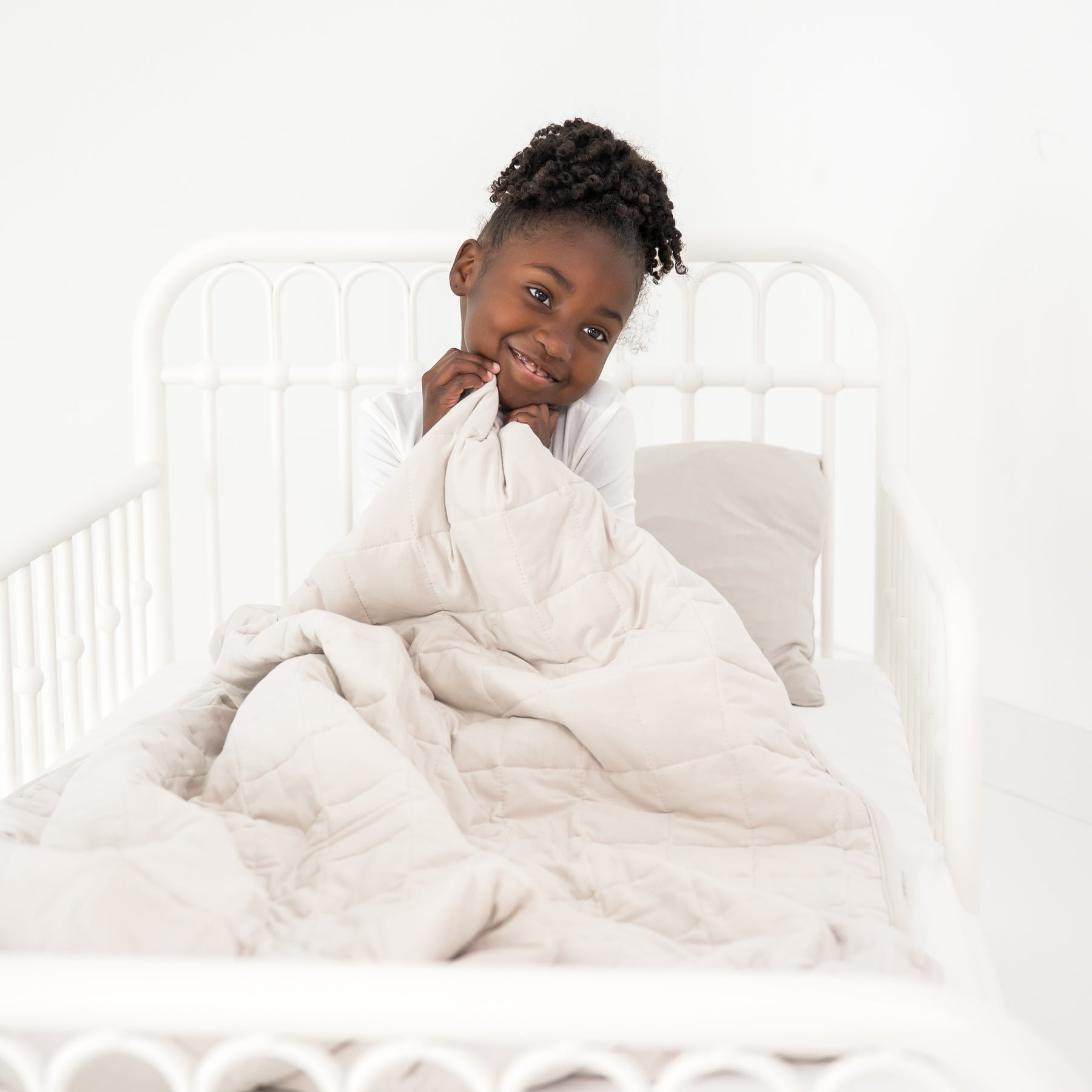 Child cozy in a toddler bed with a creamy off white blanket