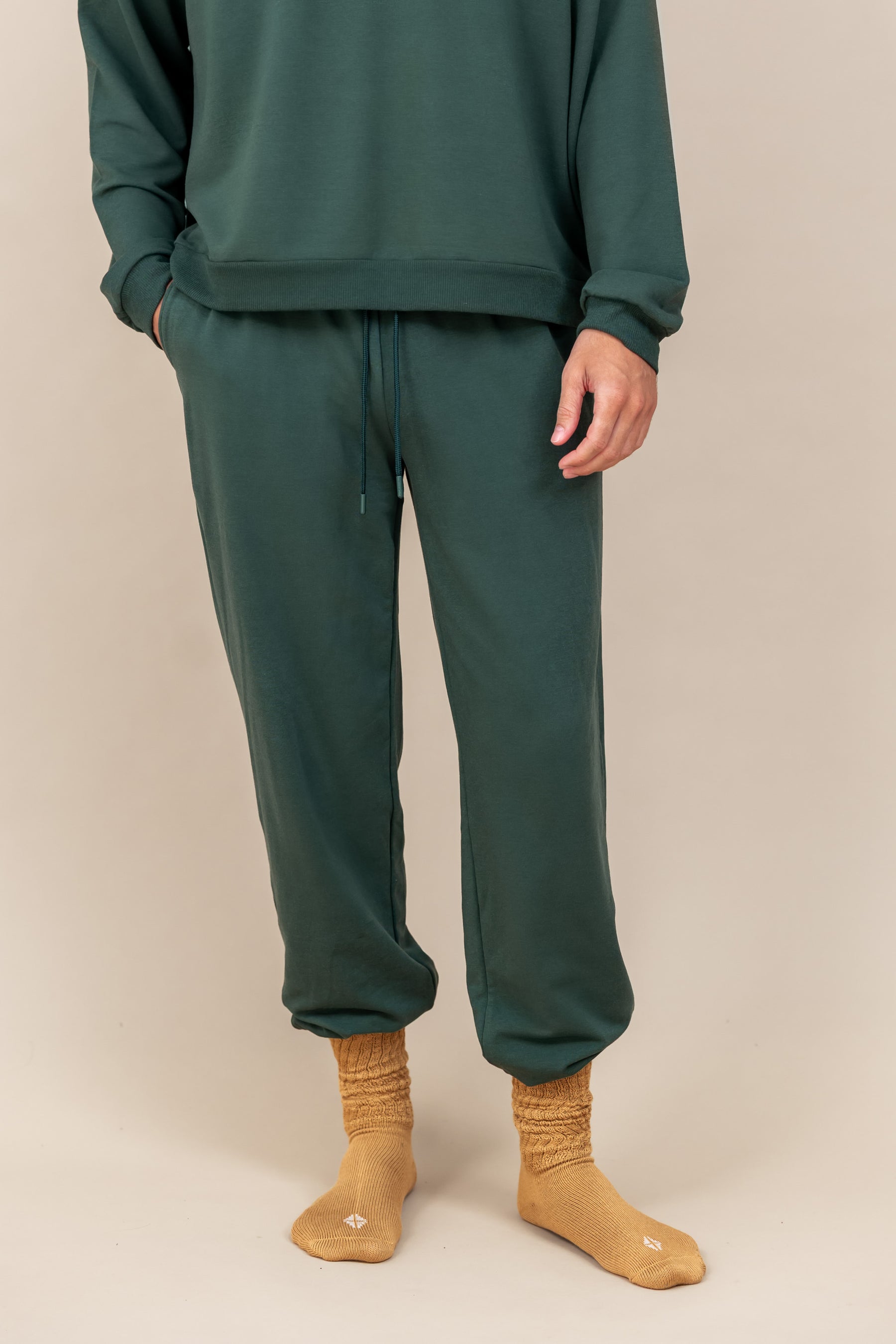 Modal wearing Adult Scrunch Socks in Ochre color while wearing green jogger set on a beige background