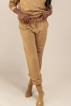 Modal wearing Women's Jogger Pants in Ochre color under similar color women's sweatshirt on a beige background