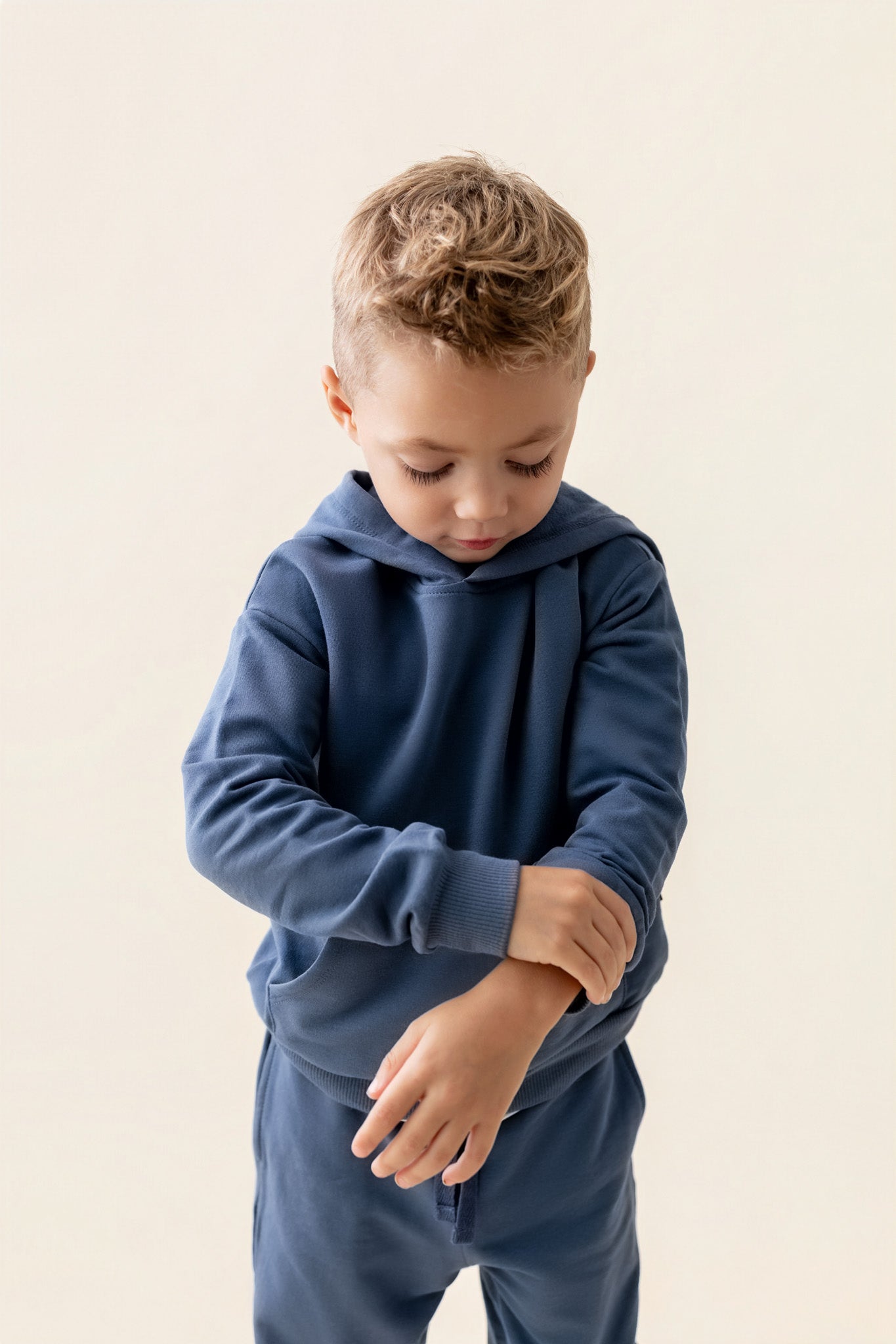 Boy wearing Hoodie in Oxford color over oxford pants on a beige background