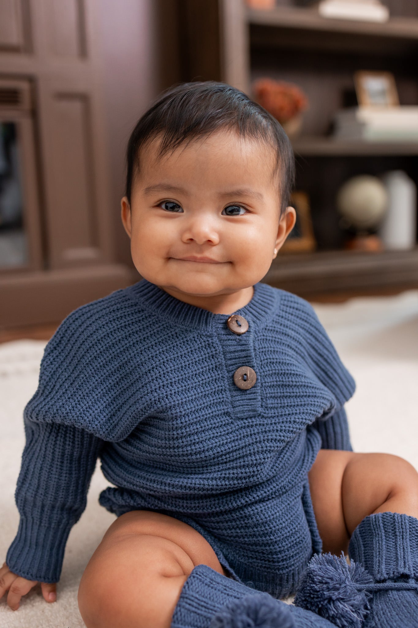 Baby smiling in Chunky Knit Romper and Knit booties in oxford