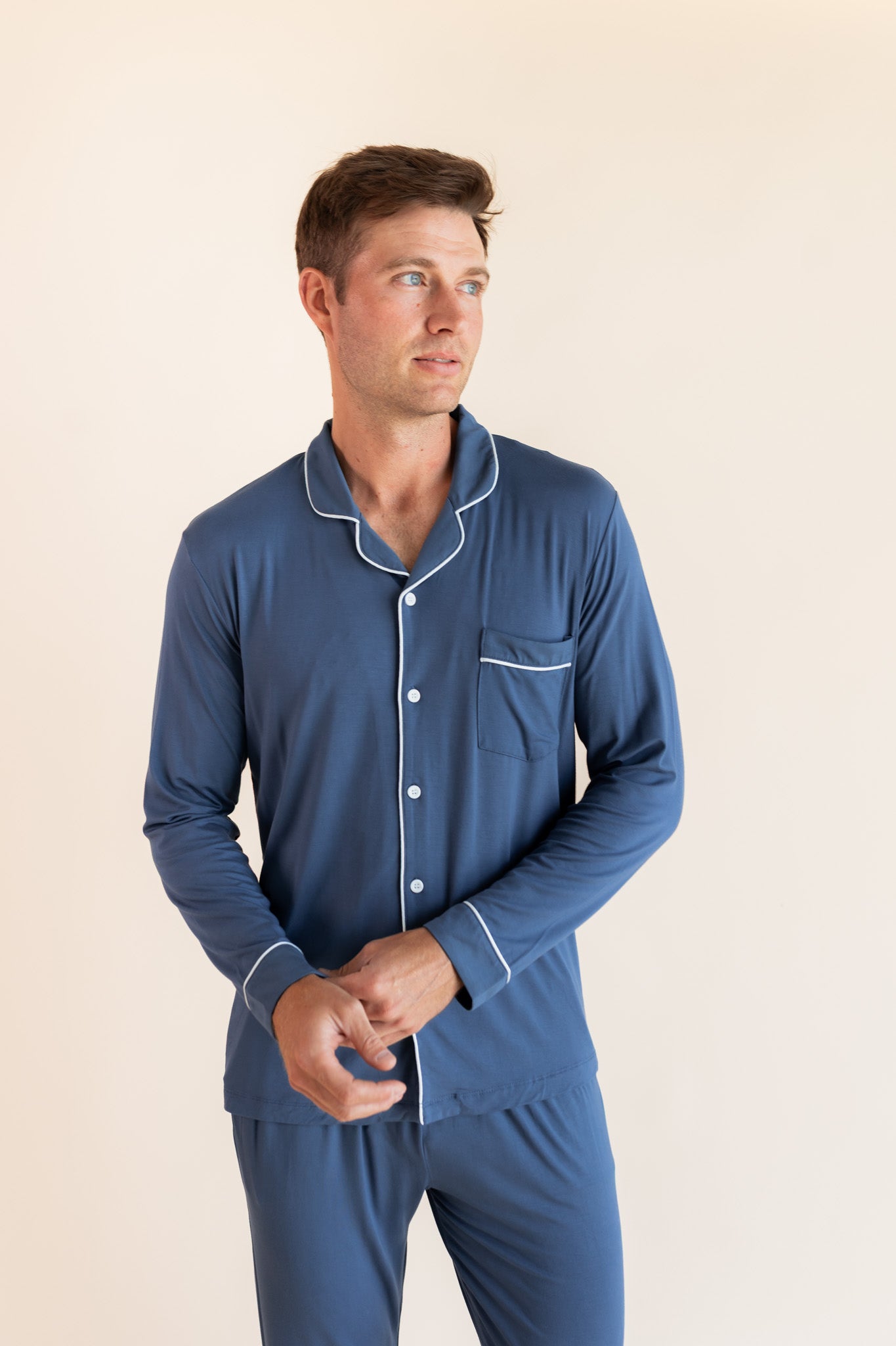 Model posing in Men's Long Sleeve Pajama Set in Oxford on a beige background
