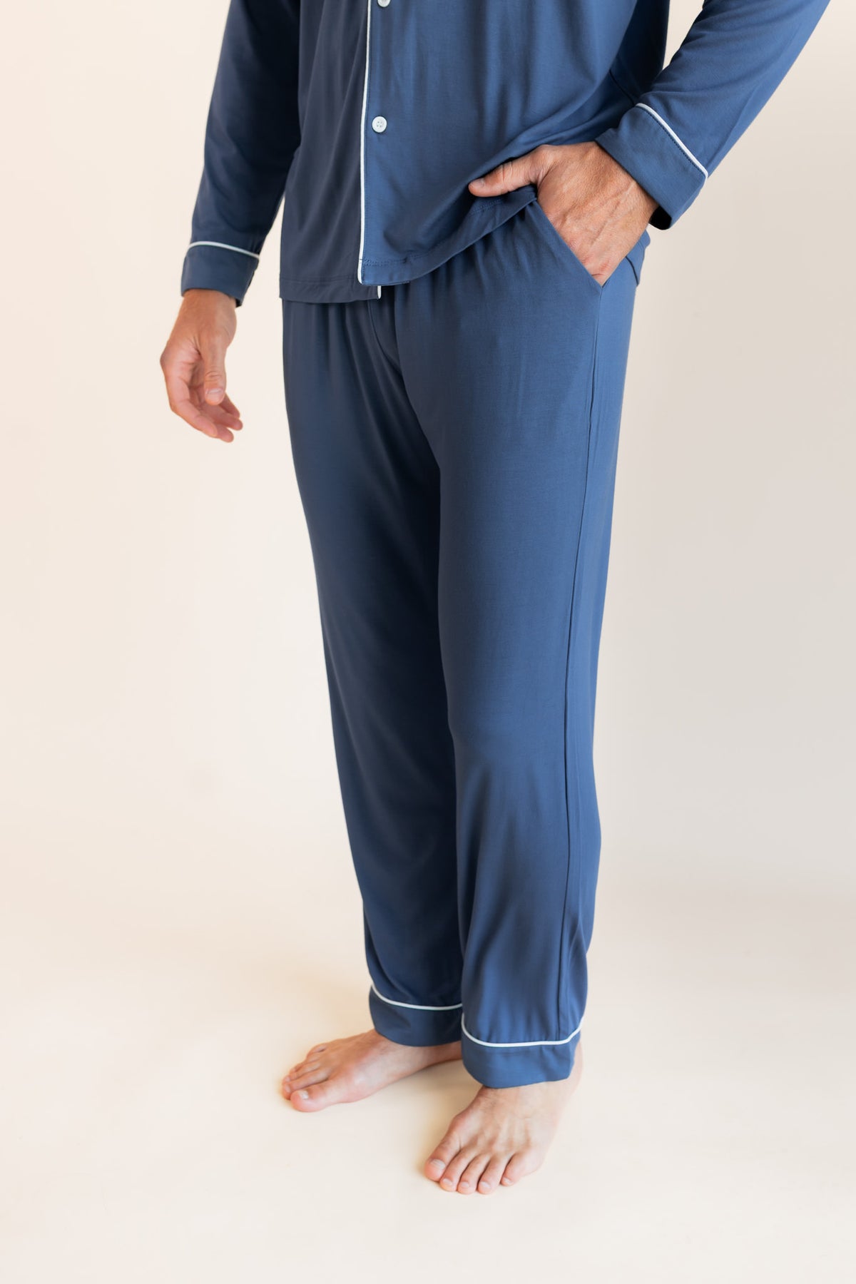 Model showcasing the pockets on Men's Long Sleeve Pajama Set in Oxford on a beige background