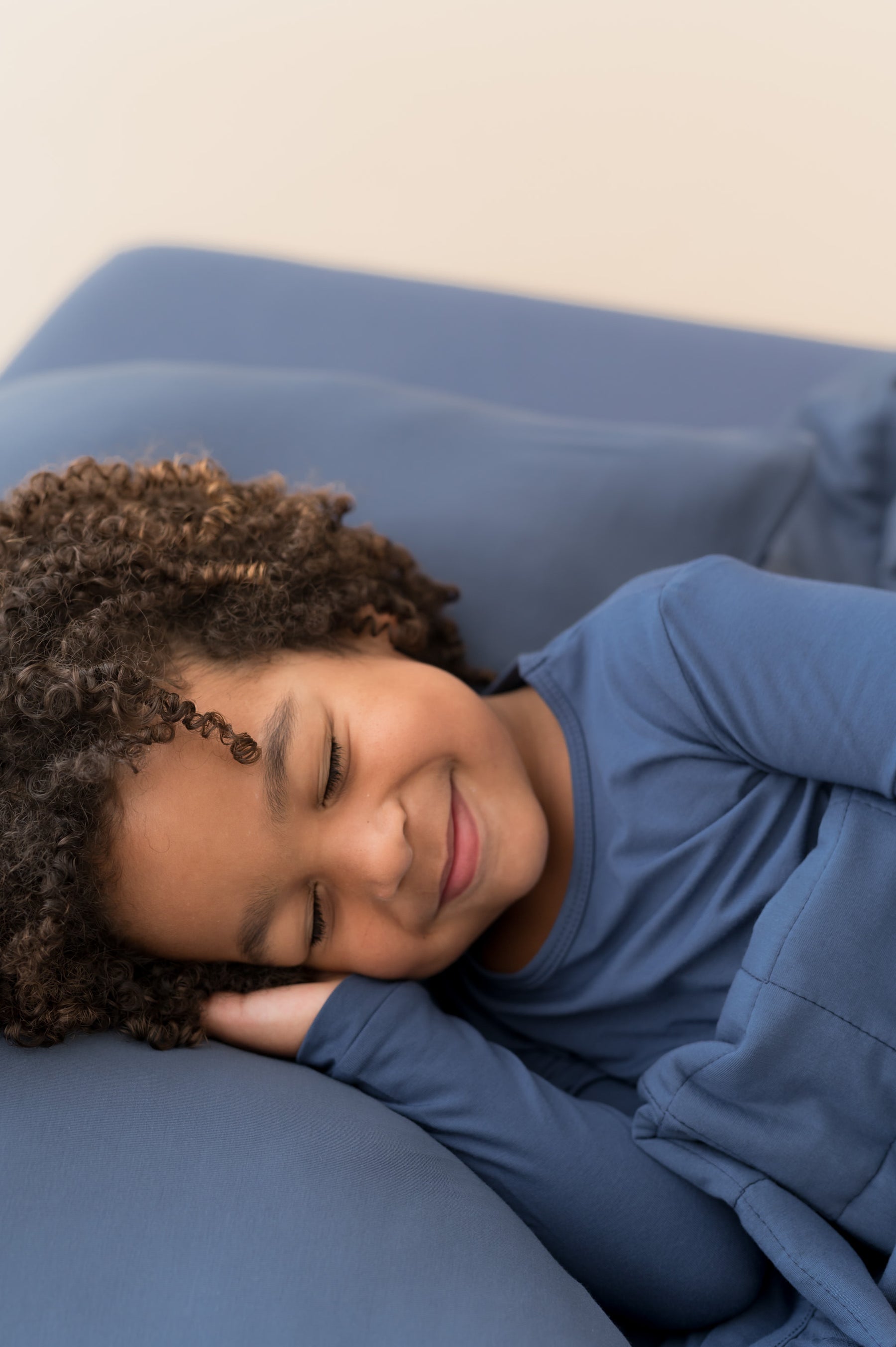 Boy sleeping on Standard Pillowcase in Oxford wearing similar color shirt and covered with Oxford blanket on oxford sheet