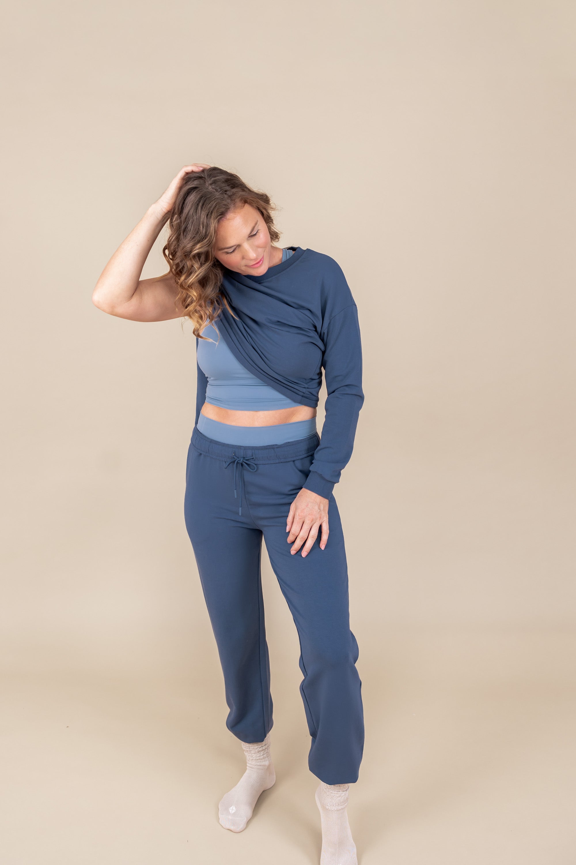 Modal wearing Women's Jogger Pants in Oxford color under flex Bra tank in breeze and sweatshirt in oxford color on a beige background
