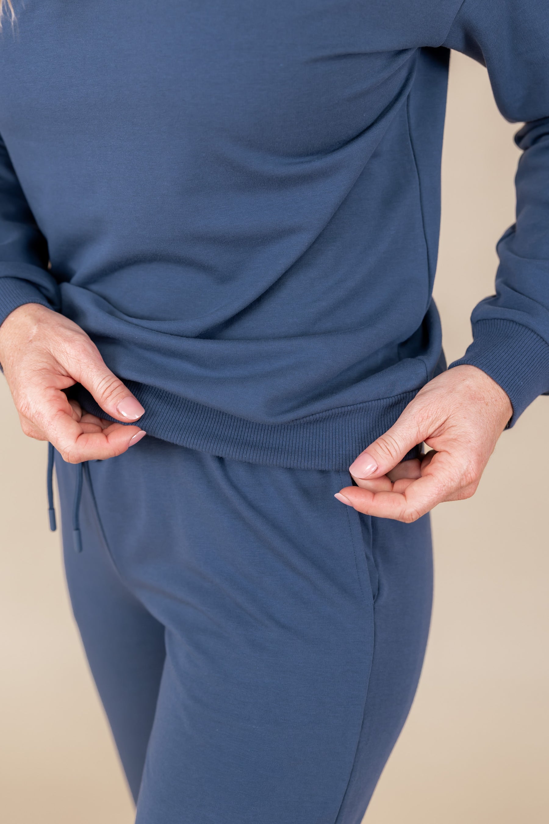 Close up of Modal wearing Women's sweatshirt in Oxford color over similar color jogger pants on a beige background