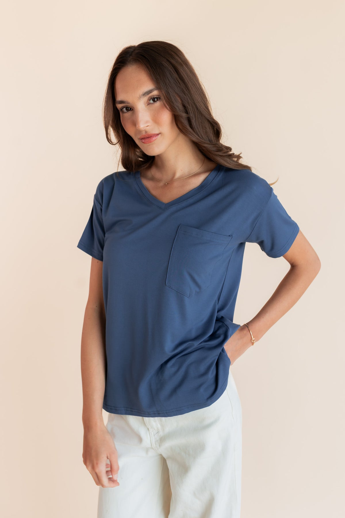 Model wearing Women's Oversized V-Neck Tee in Oxford over white pants on a beige background