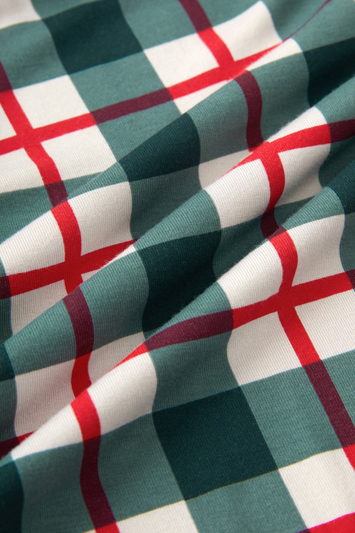 A close-up of draped fabric with a green, white, and red plaid pattern.