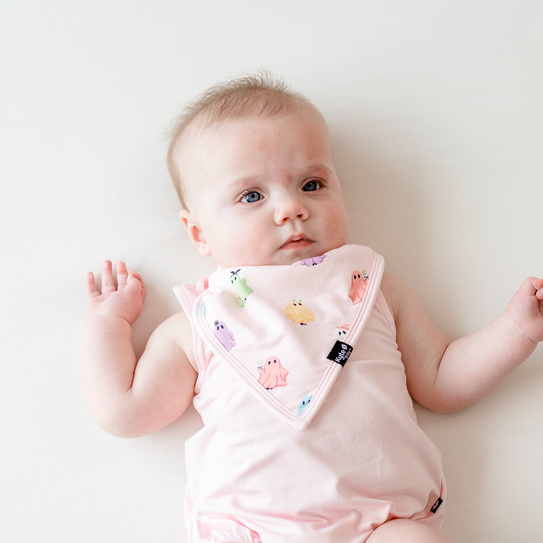 Infant laying on a light neutral wearing the Bib in Pastel Ghost paired with a Sakura Spaghetti Strap leotard