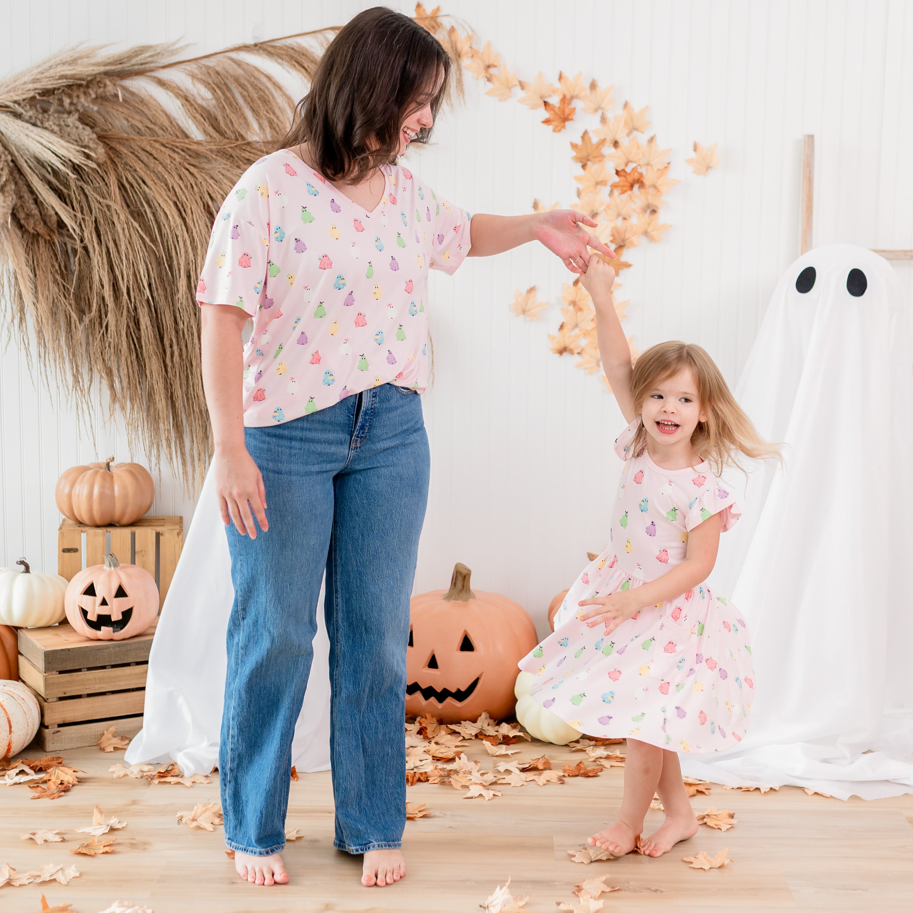 Mother and daughter matching in Pastel Ghosts in front of a fall backdrop. Mother wearing the Relaxed Women's V-neck is twirling her daughter in the Pocket Dress
