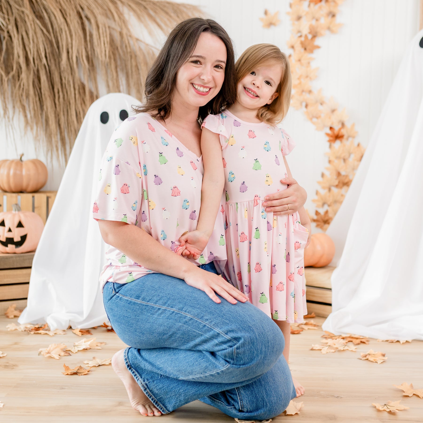 Mother and daughter matching in Pastel Ghosts in front of a Fall inspired backdrop. Mother wearing the Women's Relaxed V-neck and young girl wearing the Pocket Dress