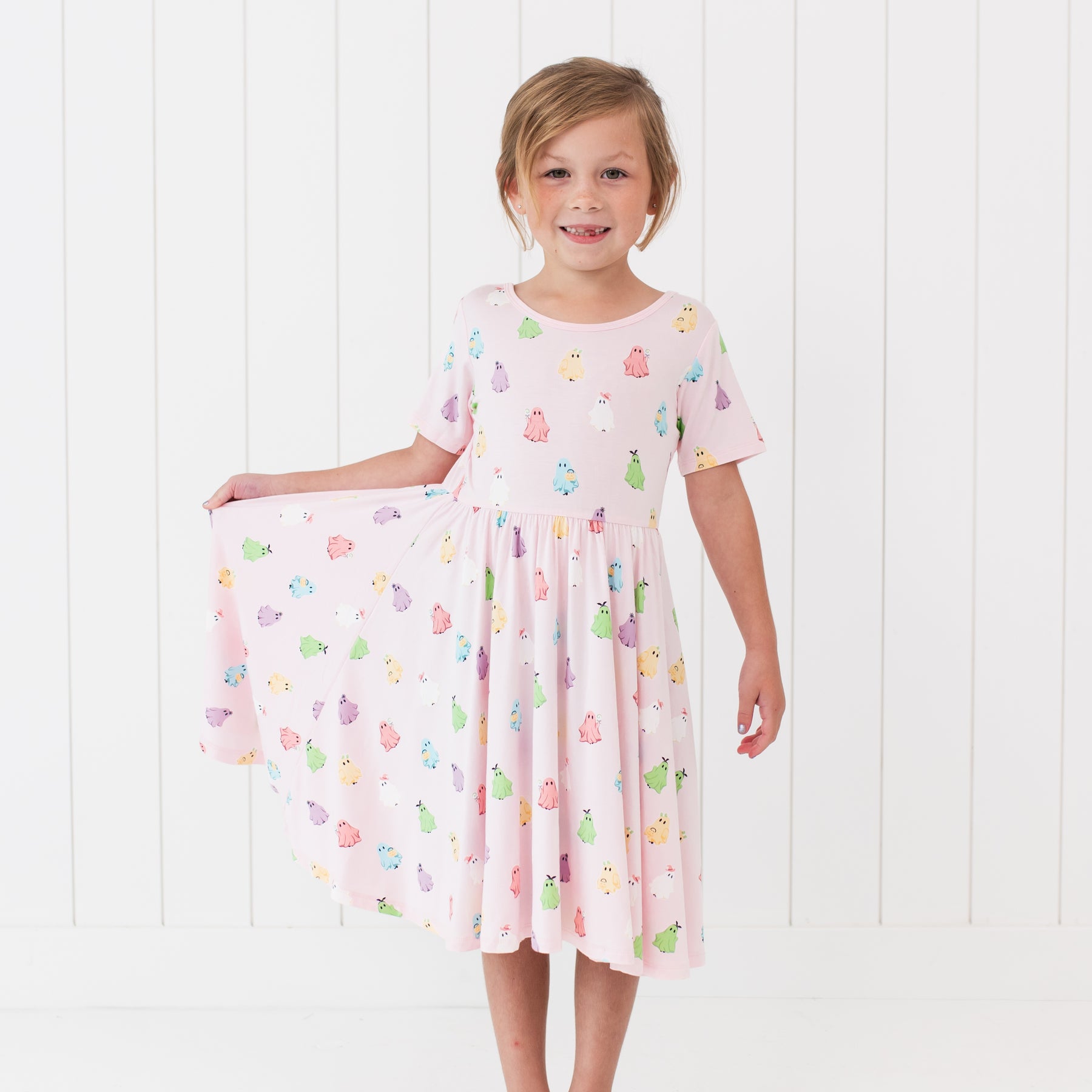 Young girl wearing a pink dress with colorful ghosts against a white background