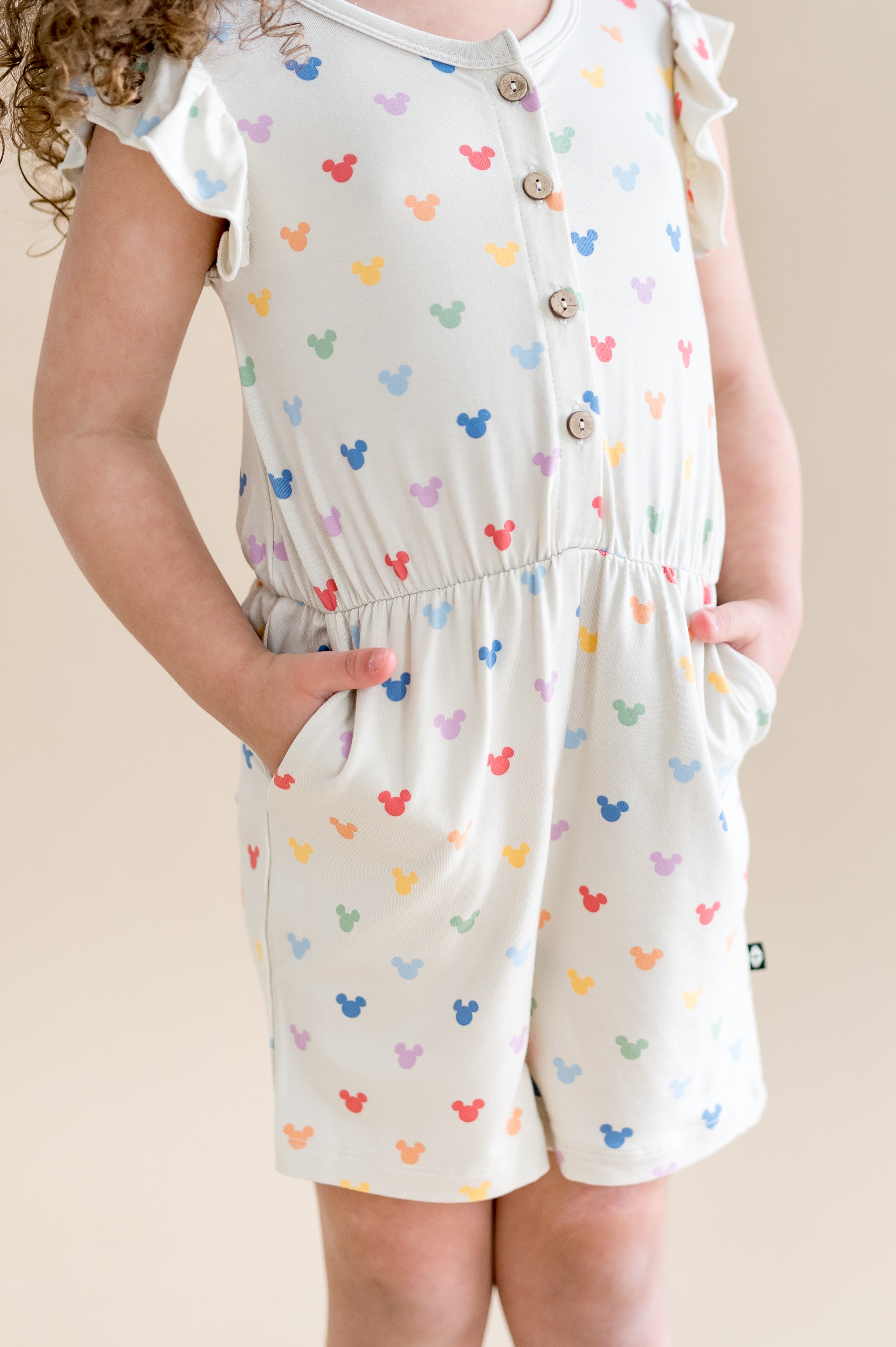 Oat colored flutter sleeve romper with mickey head pattern with buttons and pockets