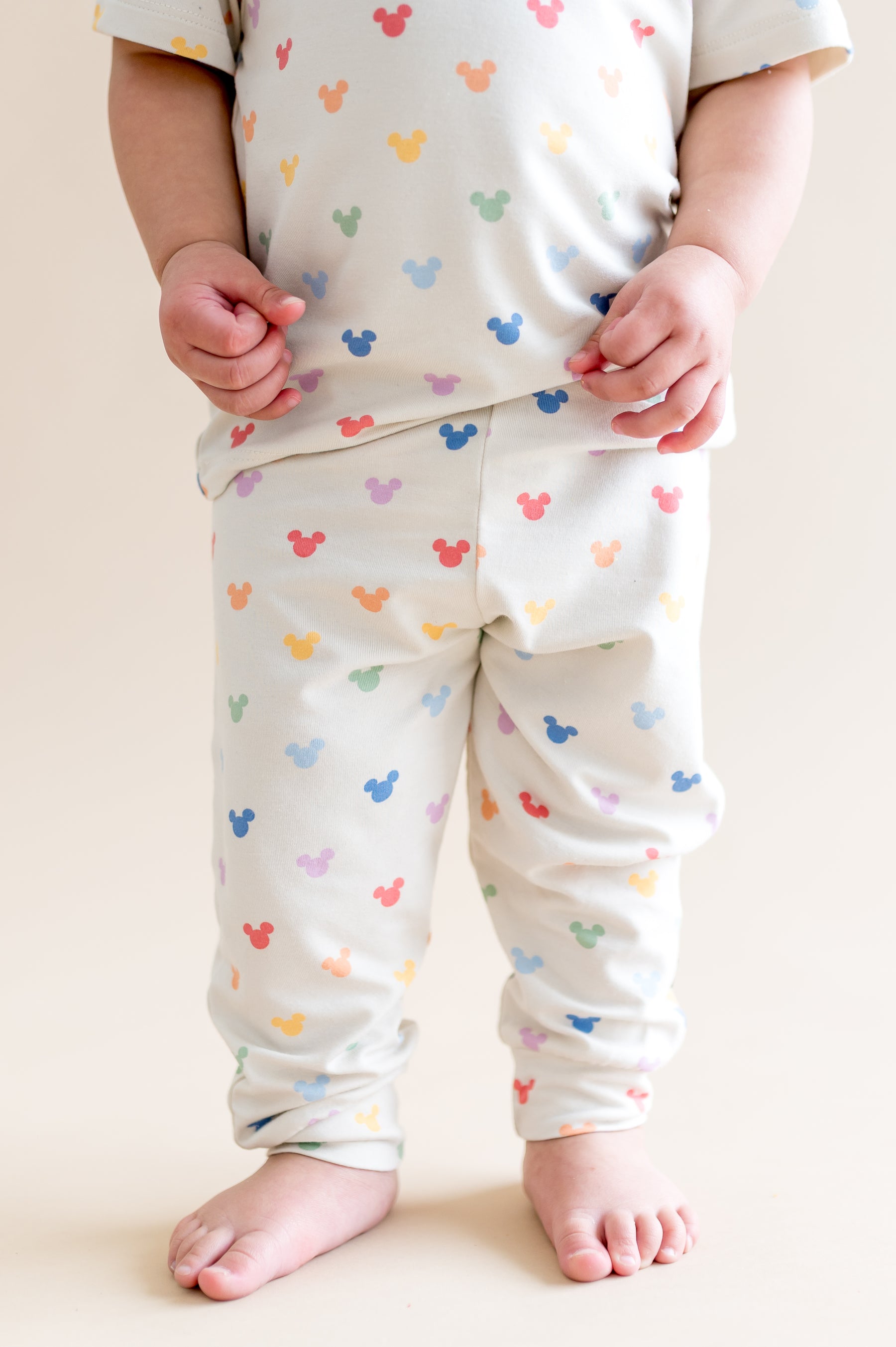 Child wearing pastel mickey head pattern pant  on a plain background
