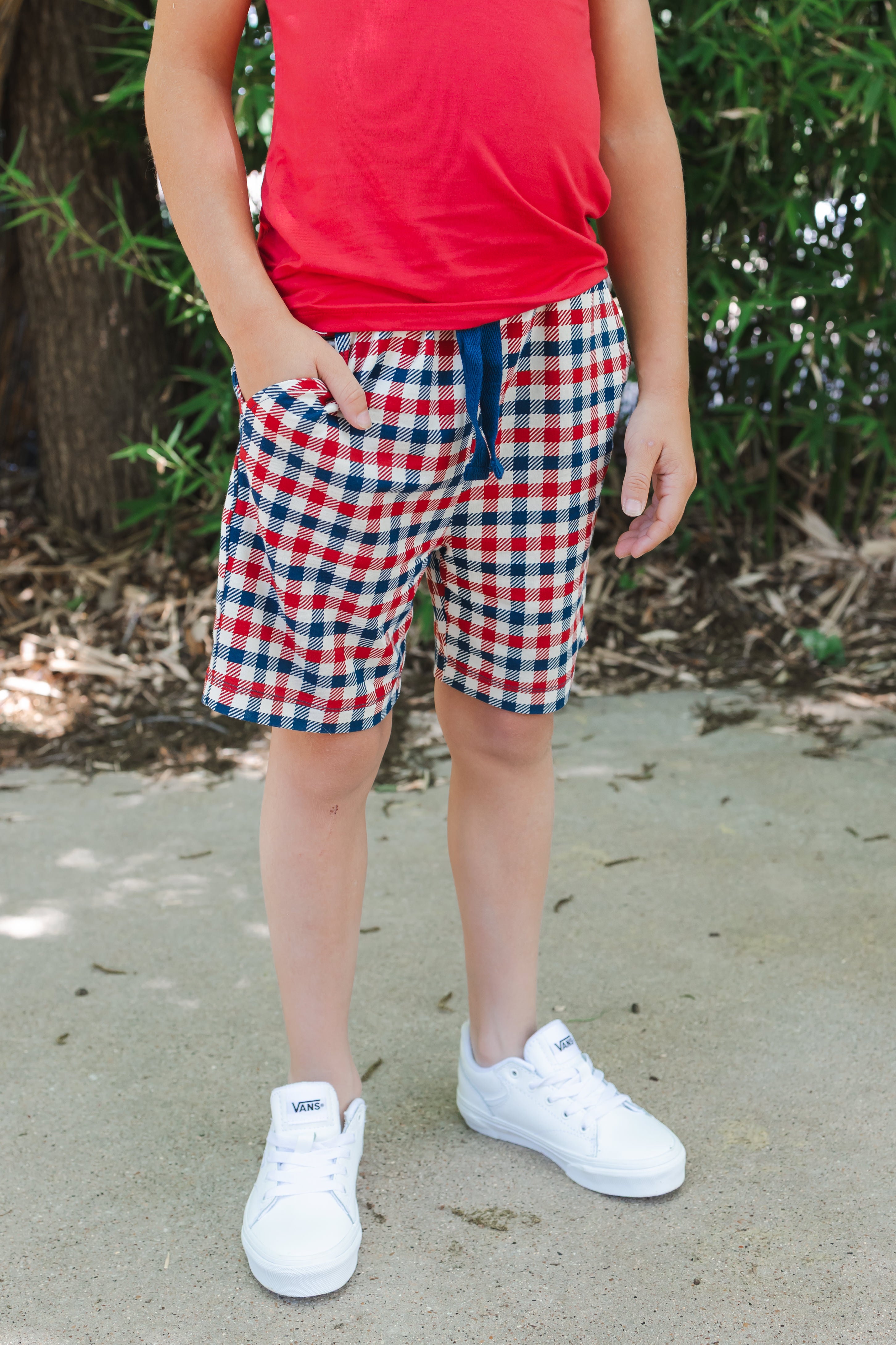 Drawstring shorts with pockets in red blue and white Patriotic Gingham check print over a red tank top and white shoes