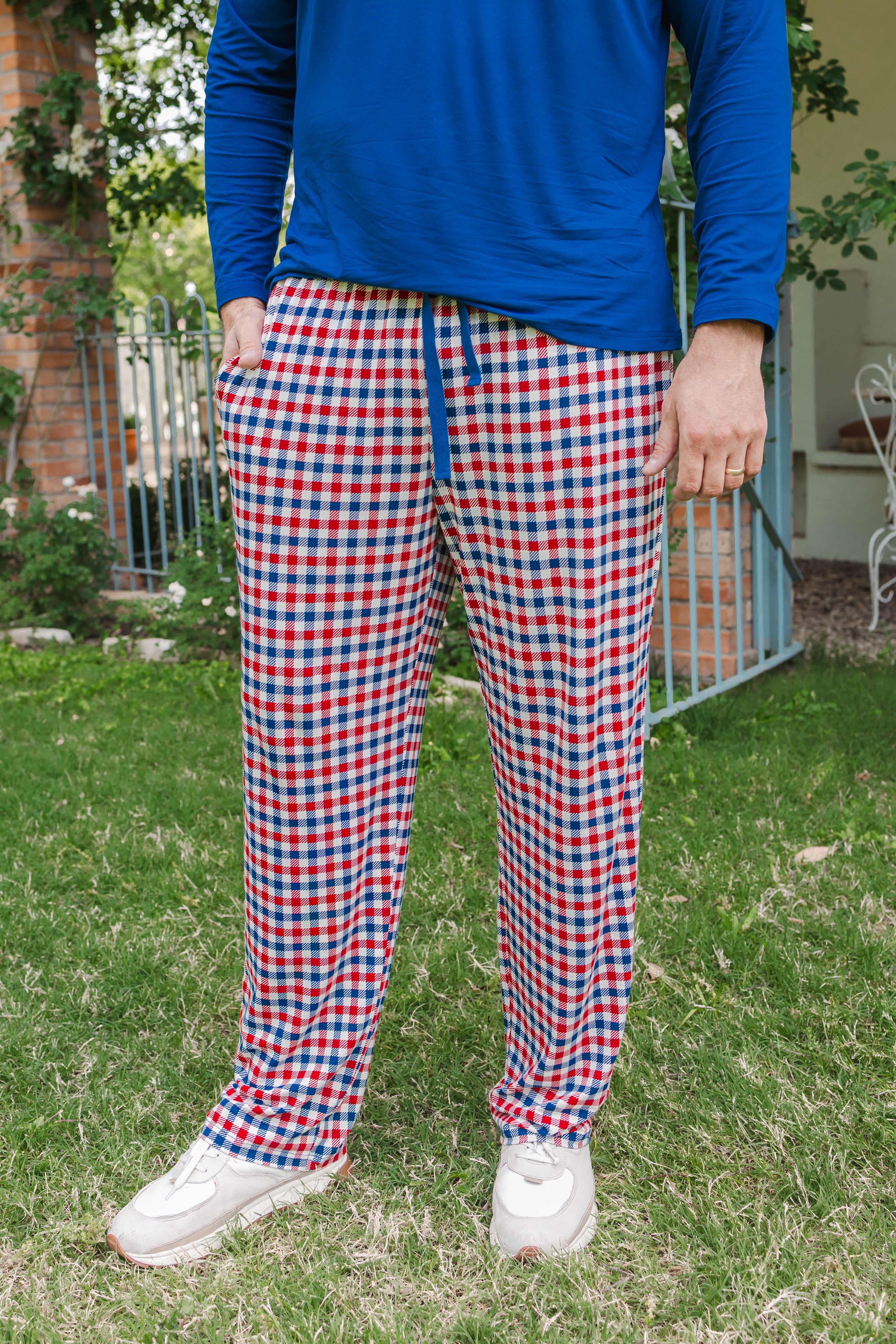 Person standing on grass wearing a red blue and white Patriotic Gingham check print Men's lounge pant under a Men's Long Sleeve Henley Top in Tahoe