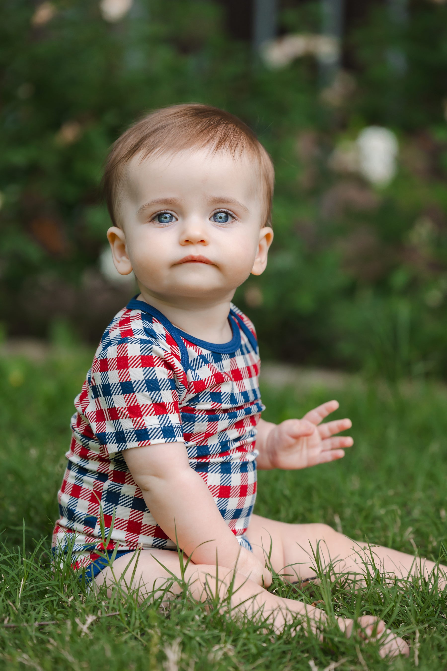 Baby in a red blue and white Patriotic Gingham check print short sleeve Bodysuit sitting on a grass